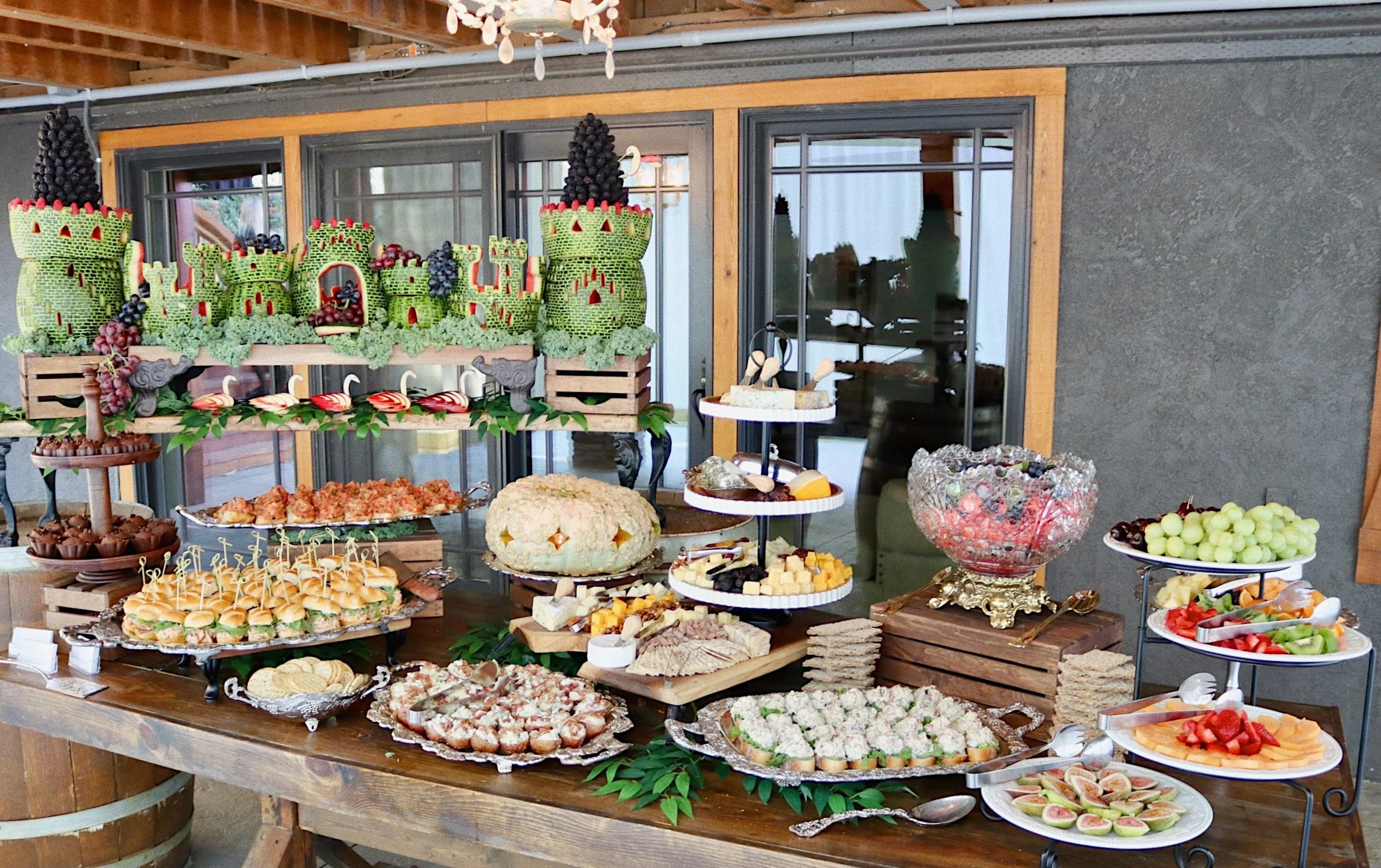 A complete appetizer table artistically presented with a watermelon castle centerpiece, prepared by Silver Platter Catering