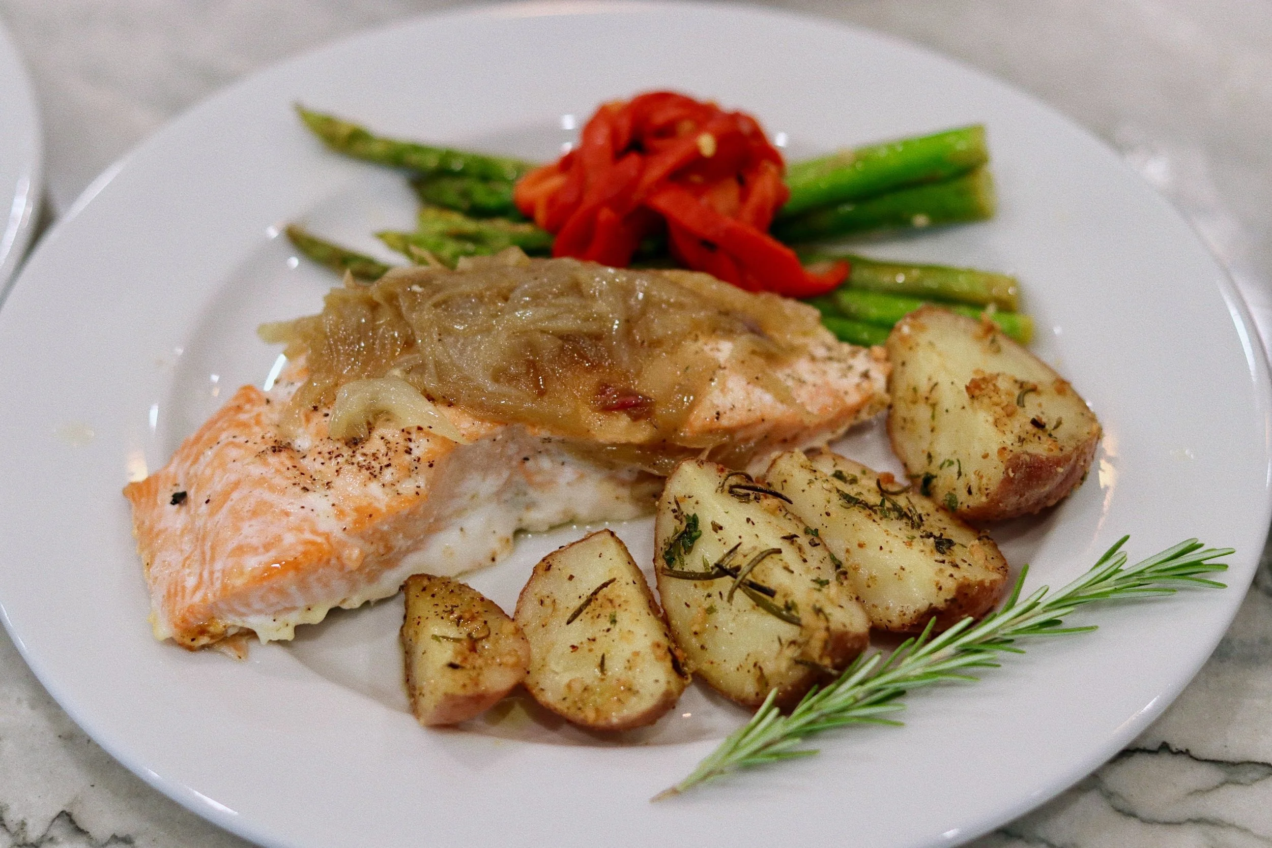 Plated salmon dinner topped with caramelized leeks, prepared by Silver Platter Catering