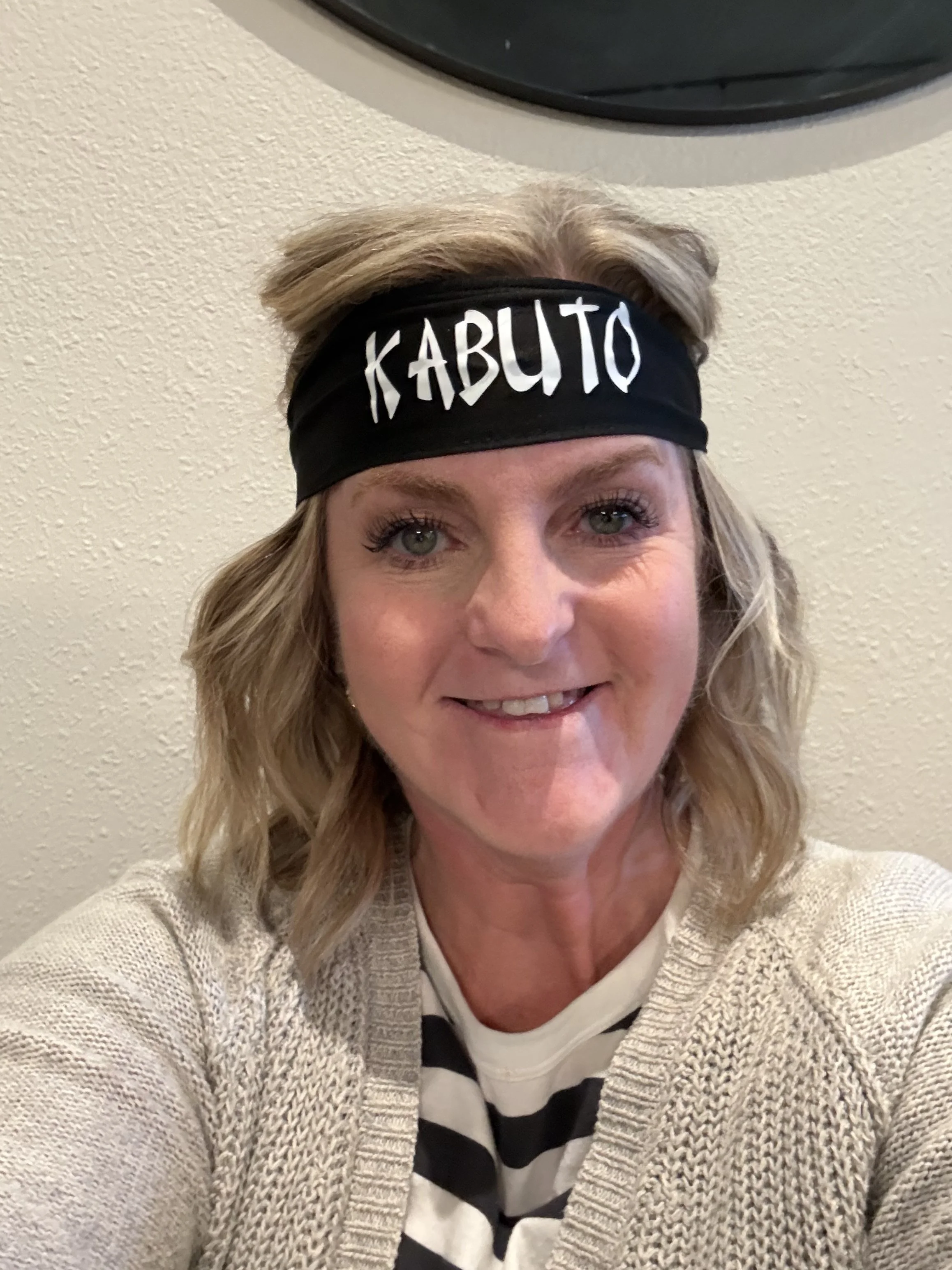 A woman with blonde hair wearing a black headband with the word 'KABUTO' written on it, smiling at the camera.