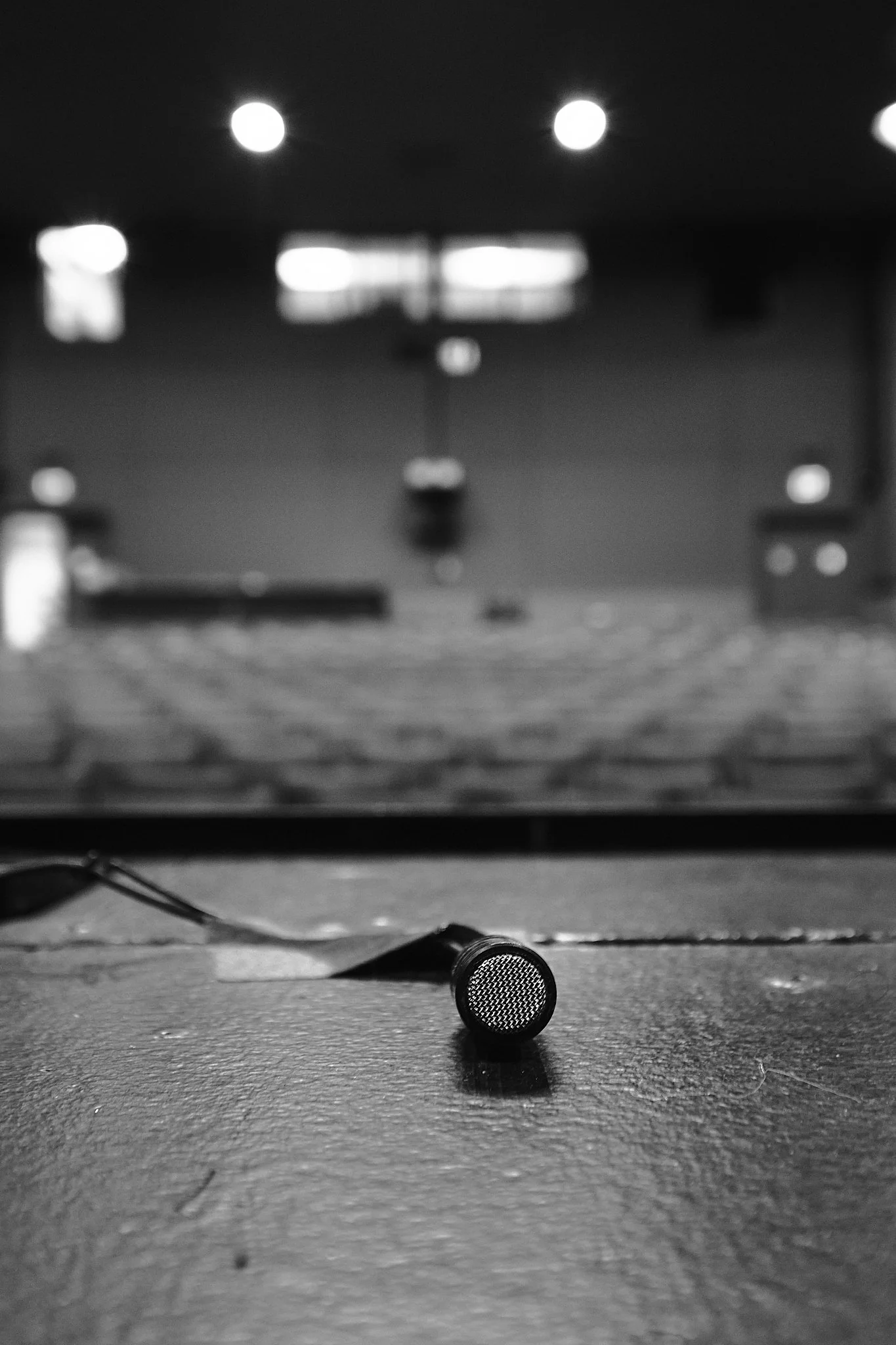 A microphone on a stage with a blurry background of bright stage lights.