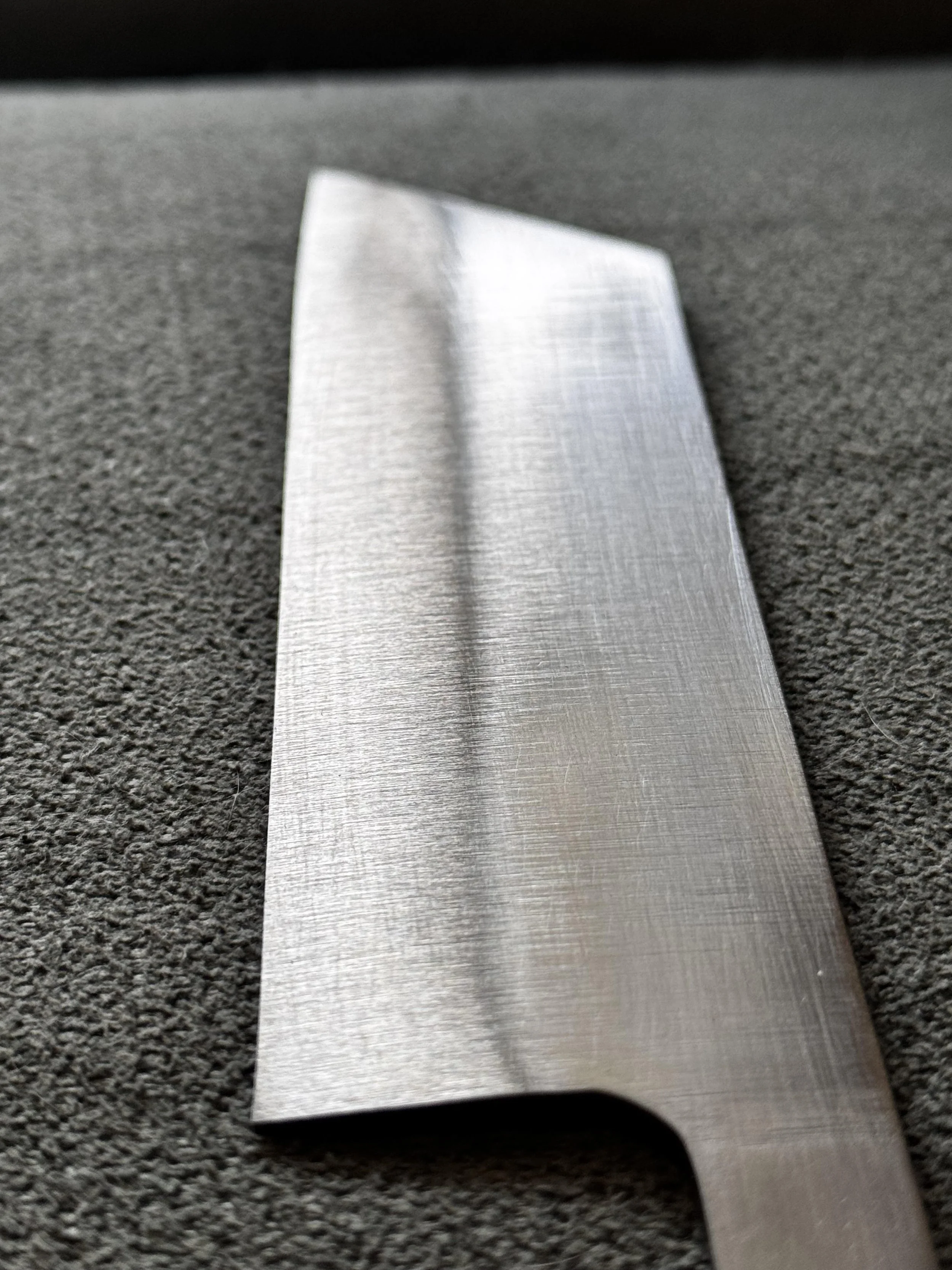Close-up of a metallic straightedge or ruler on a textured dark surface.