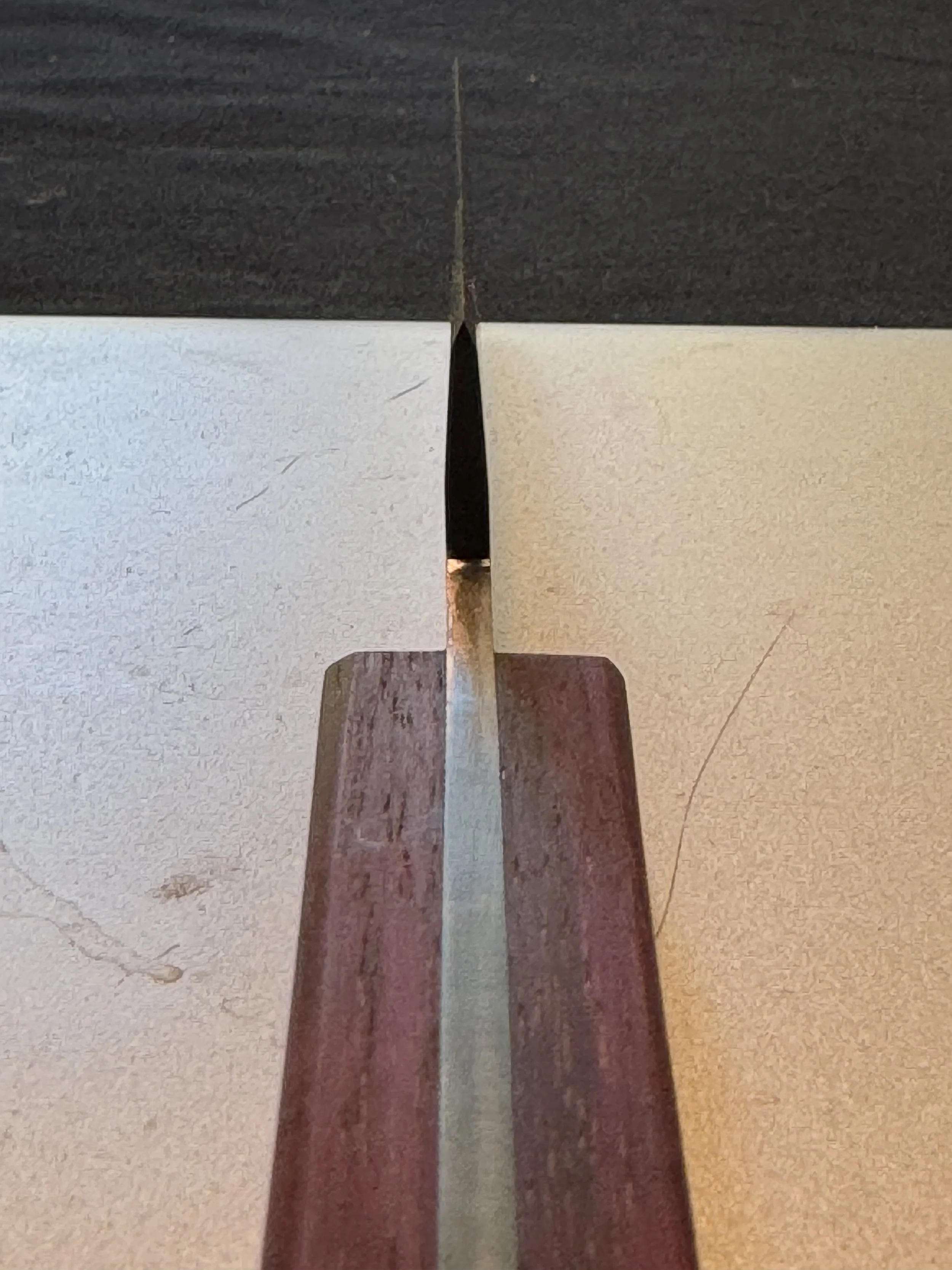 Close-up of a wooden and metal object, possibly a furniture joint, with dark and light wood sections and black and metallic parts at the center.