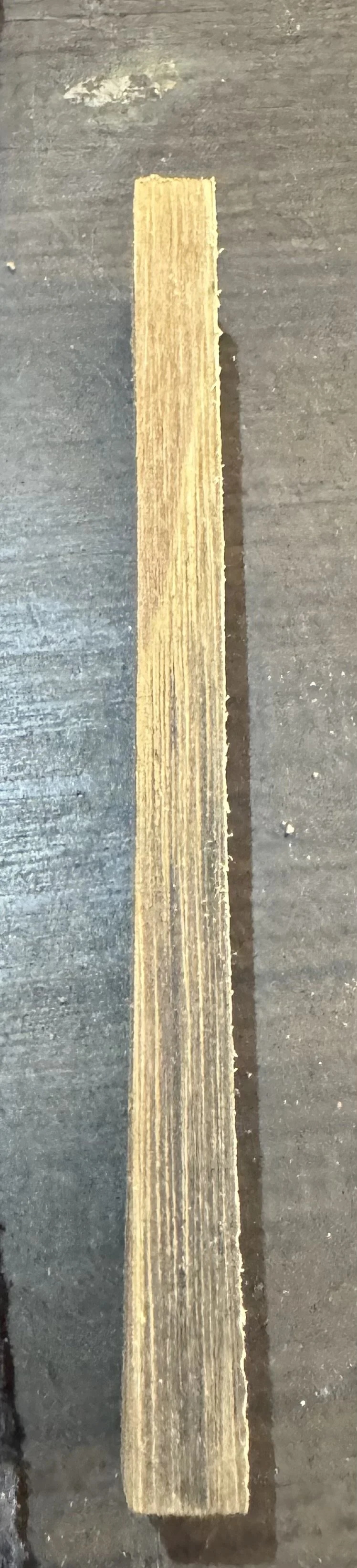 A long, narrow piece of wood placed on a dark, textured surface.