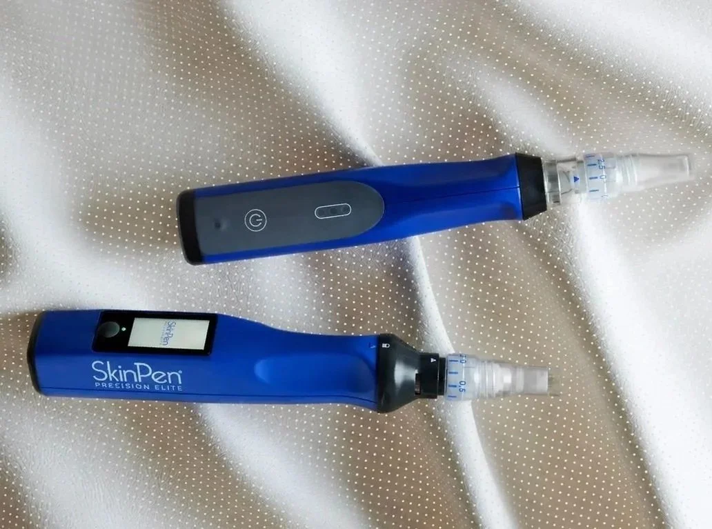 Two blue skin care devices placed on a light-colored textured fabric surface.