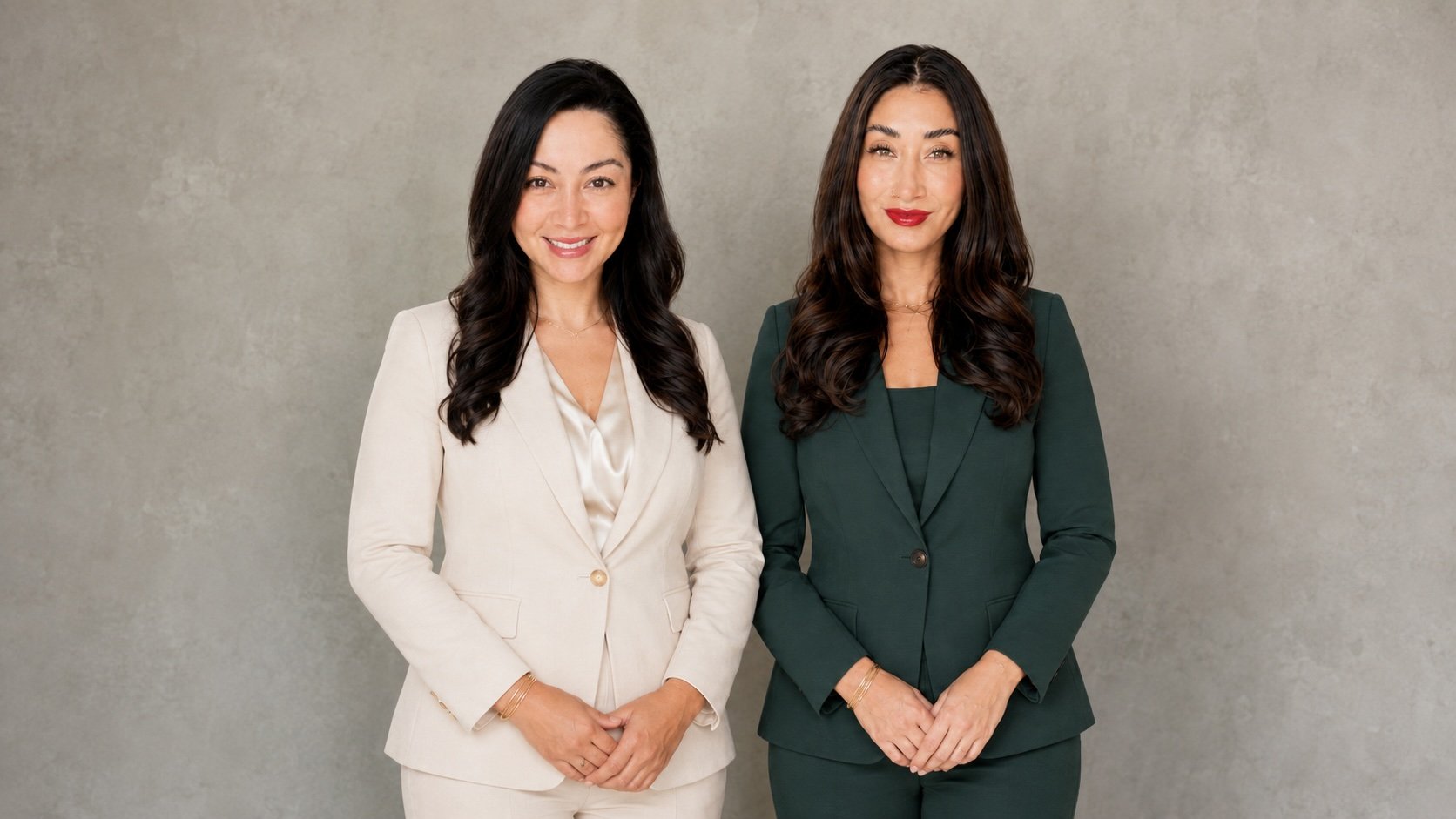 Aesthetic nurse injectors who provide medical weight loss and injectables. Two women standing side by side, smiling at the camera, against a neutral-colored wall background. One is wearing a cream-colored suit, and the other a dark green suit.