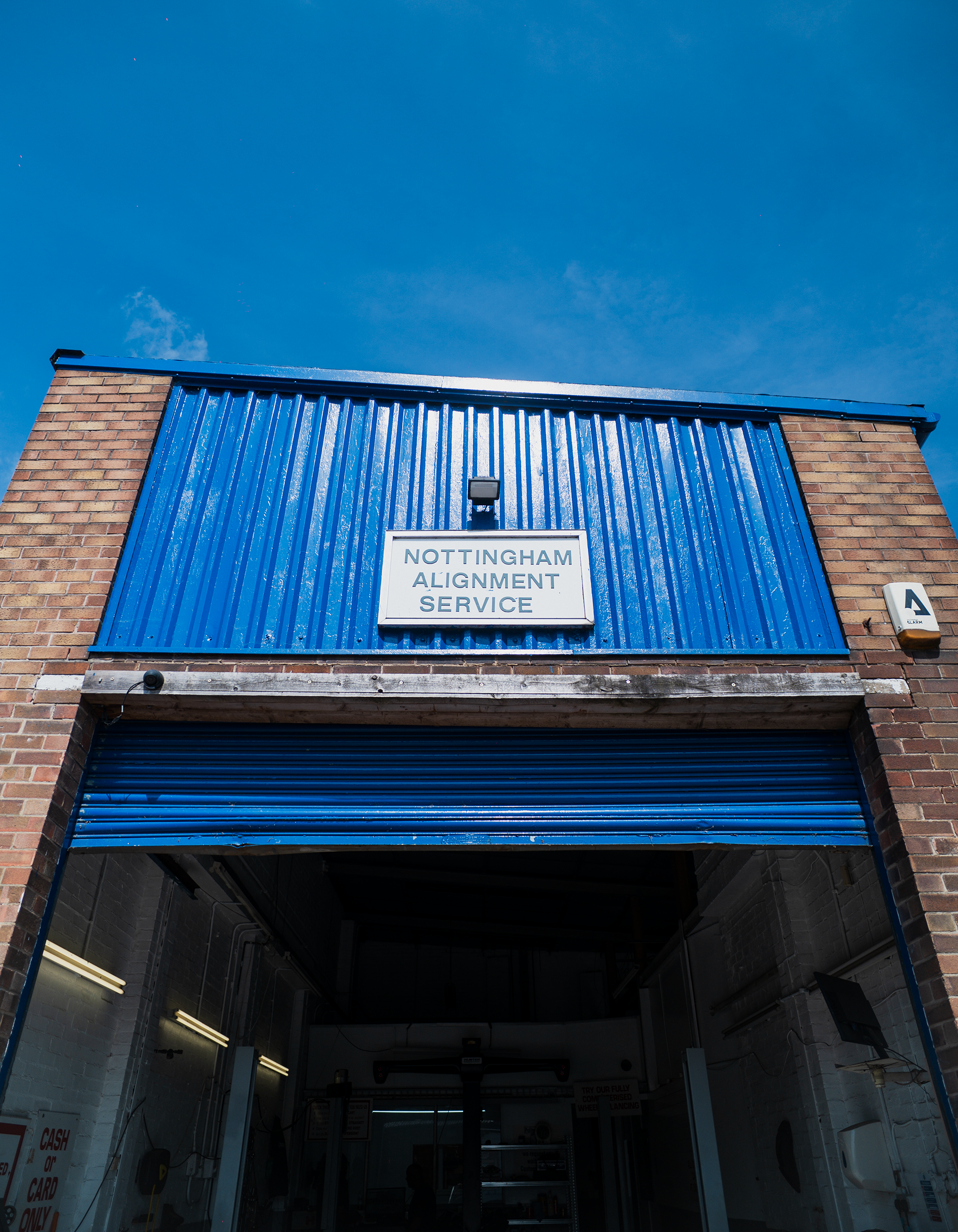 Excavation bay with blue corrugated metal walls, a sign reading 'Nottingham Alignment Service,' a covered garage area inside.