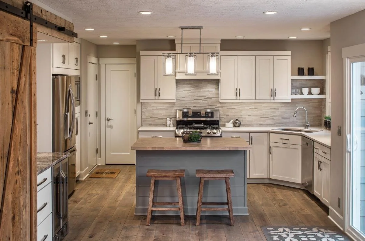 Modern kitchen with white cabinets, stainless steel appliances, a wooden island with stools, and a sliding glass door.