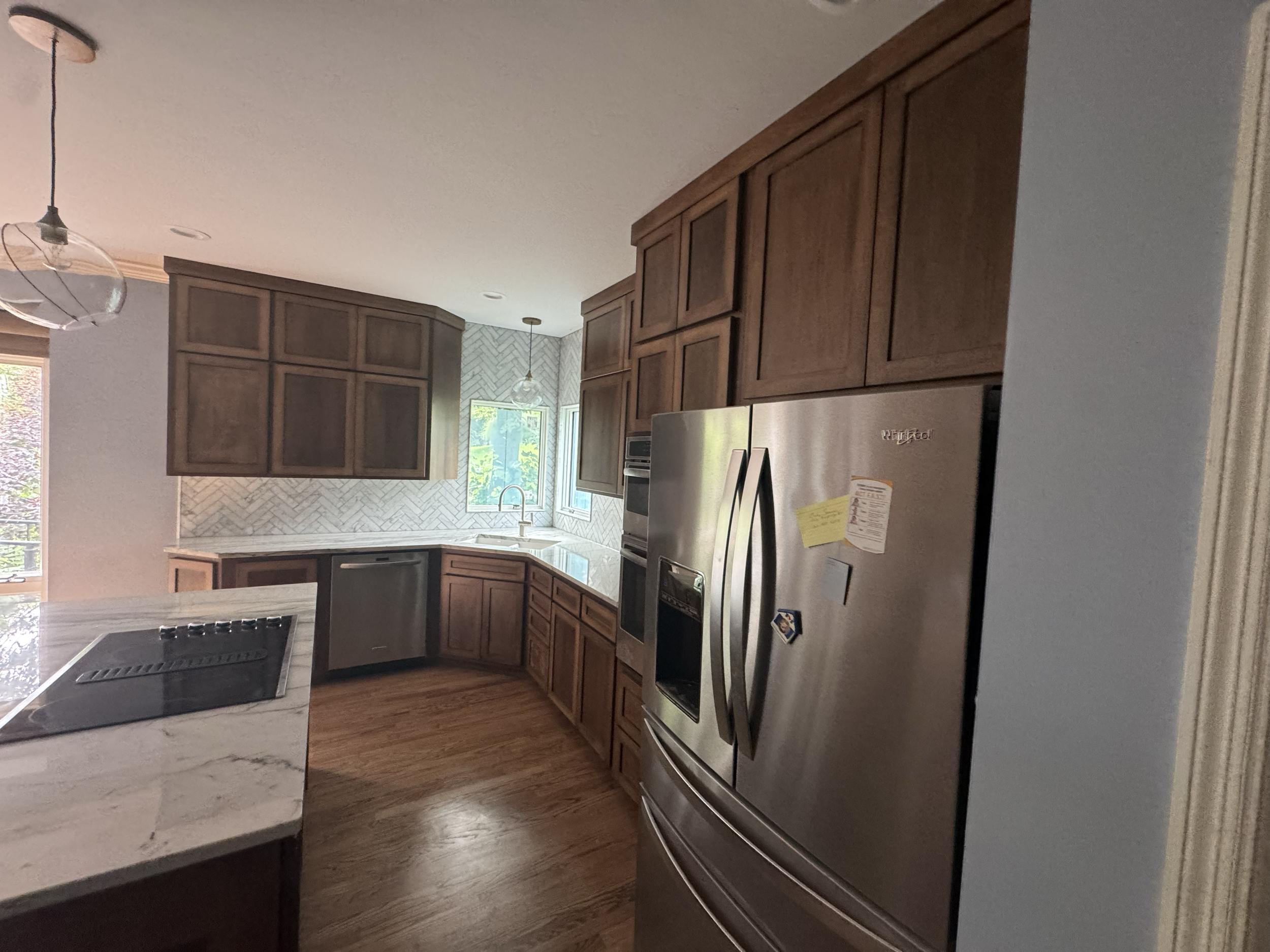 Modern kitchen with wooden cabinets, stainless steel appliances, granite countertops, and a window looking outside