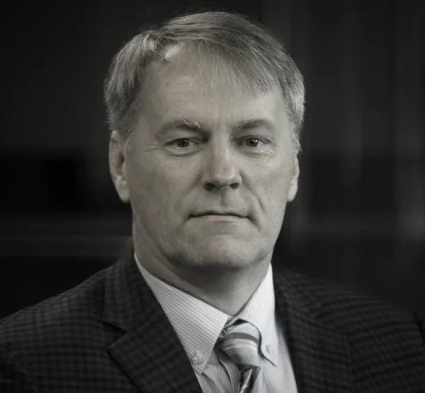 Black and white portrait of a middle-aged man with short hair, wearing a suit and tie.