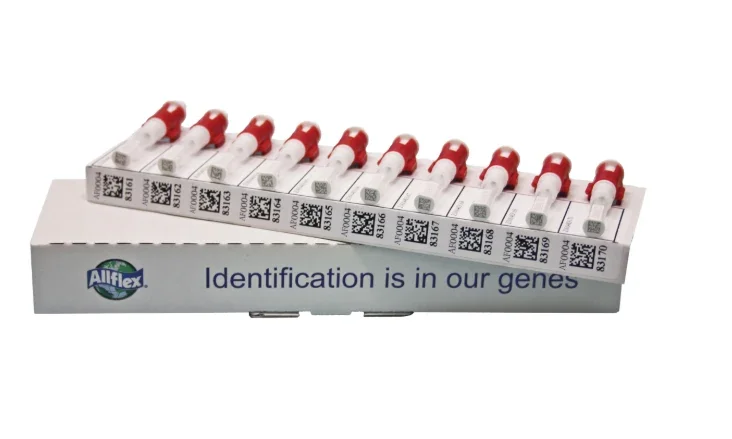 A box of blood collection tubes with red caps and QR codes, labeled with various numbers, and the text "Identification is in our genes" on the side.