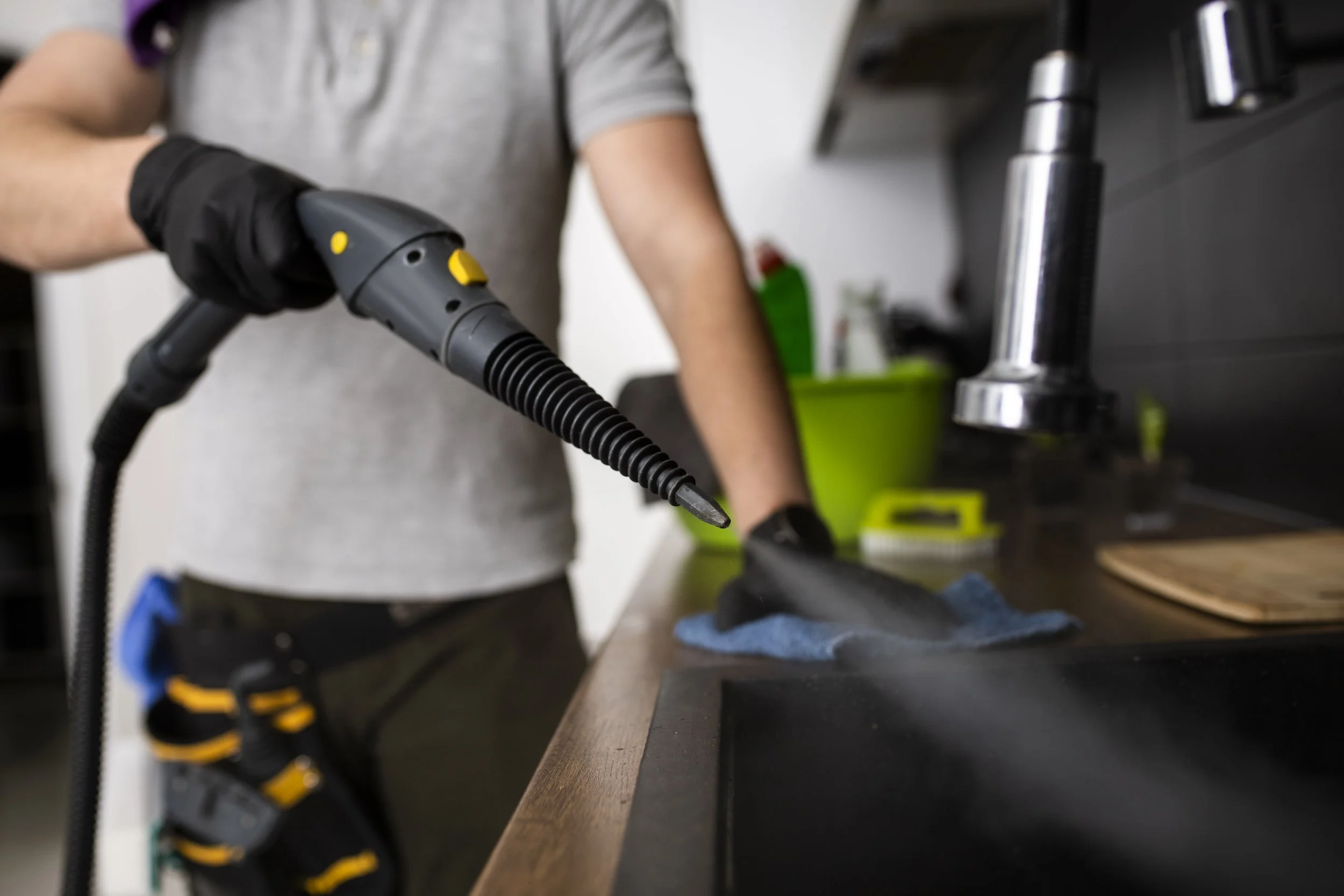 Person holding a handheld heat gun with a black and yellow cord, working on a wooden surface in a workshop.