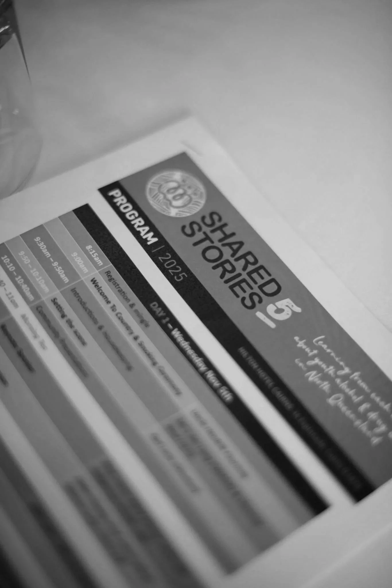 A printed program with a header that reads "Shared Stories" for an event in 2025. The program includes a schedule with times and descriptions, and appears to be placed on a flat surface.