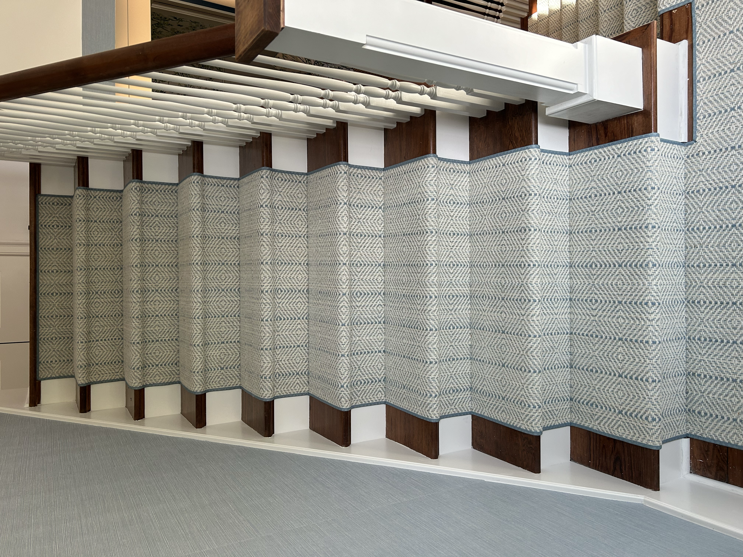 Staircase with patterned carpet runner, wooden steps, and white spindled railing on the right side.