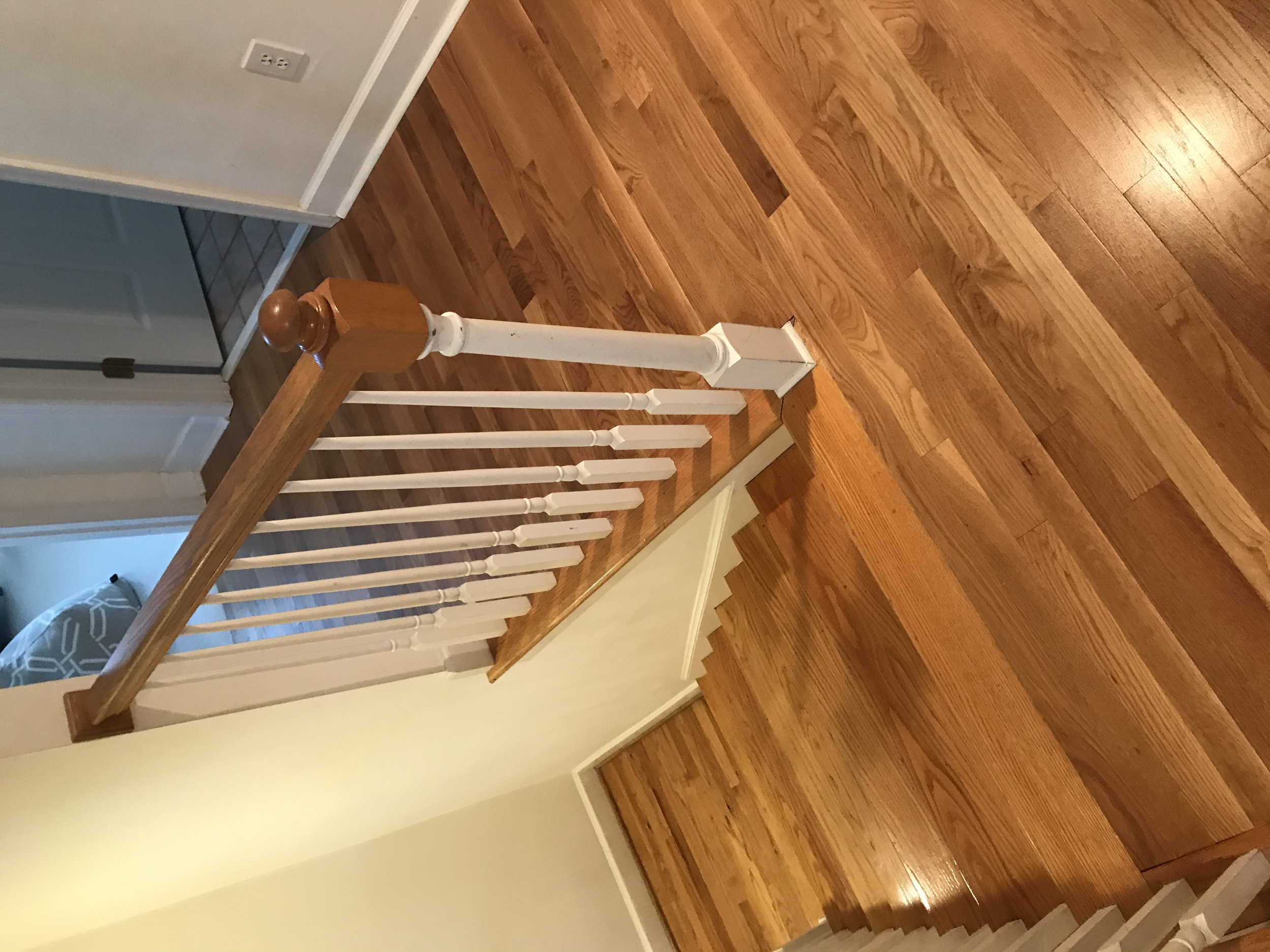 Wooden staircase with white railing and hardwood flooring in a house interior.