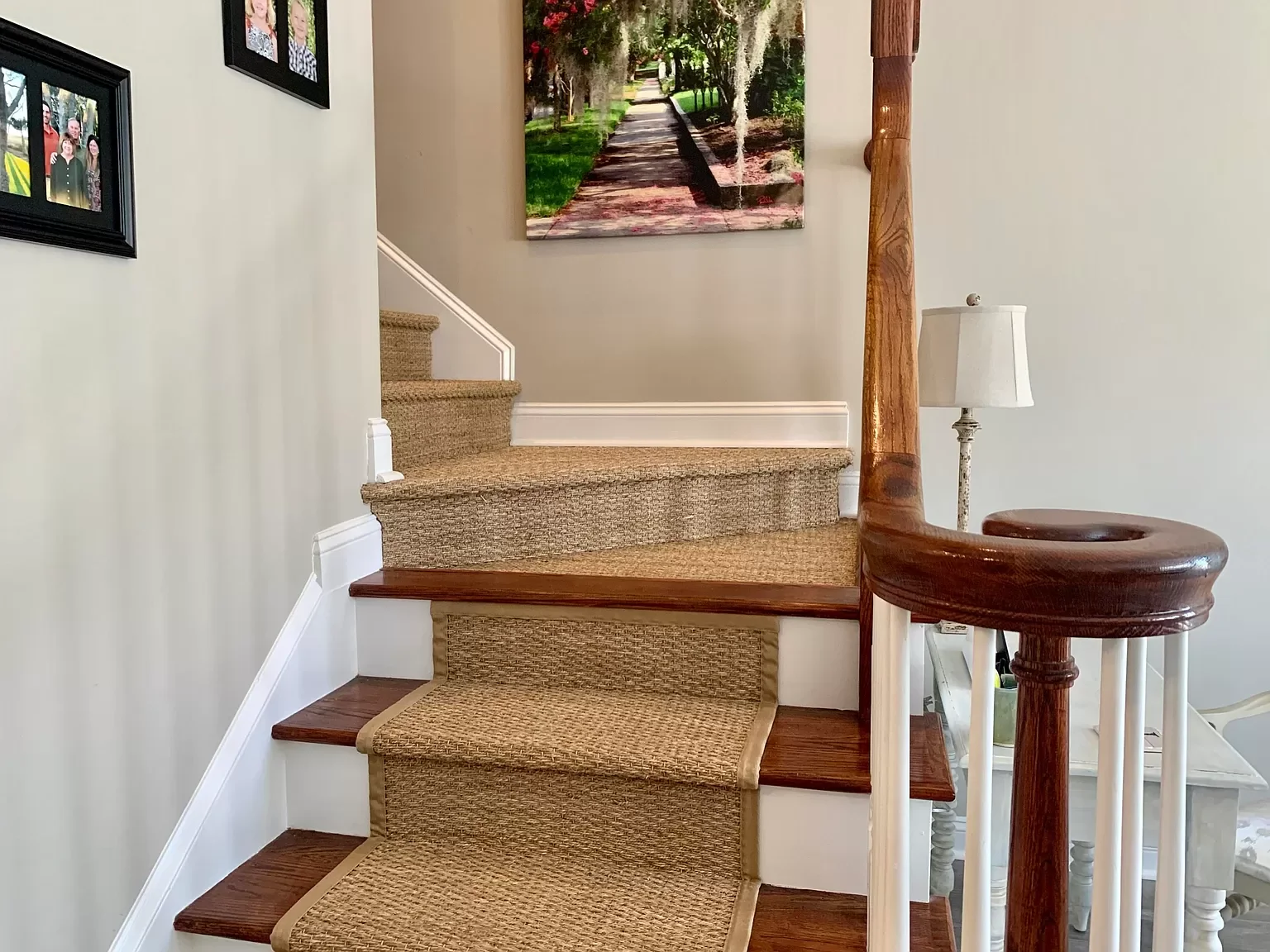A staircase with carpeted steps, a wooden handrail, and framed photographs on the wall.