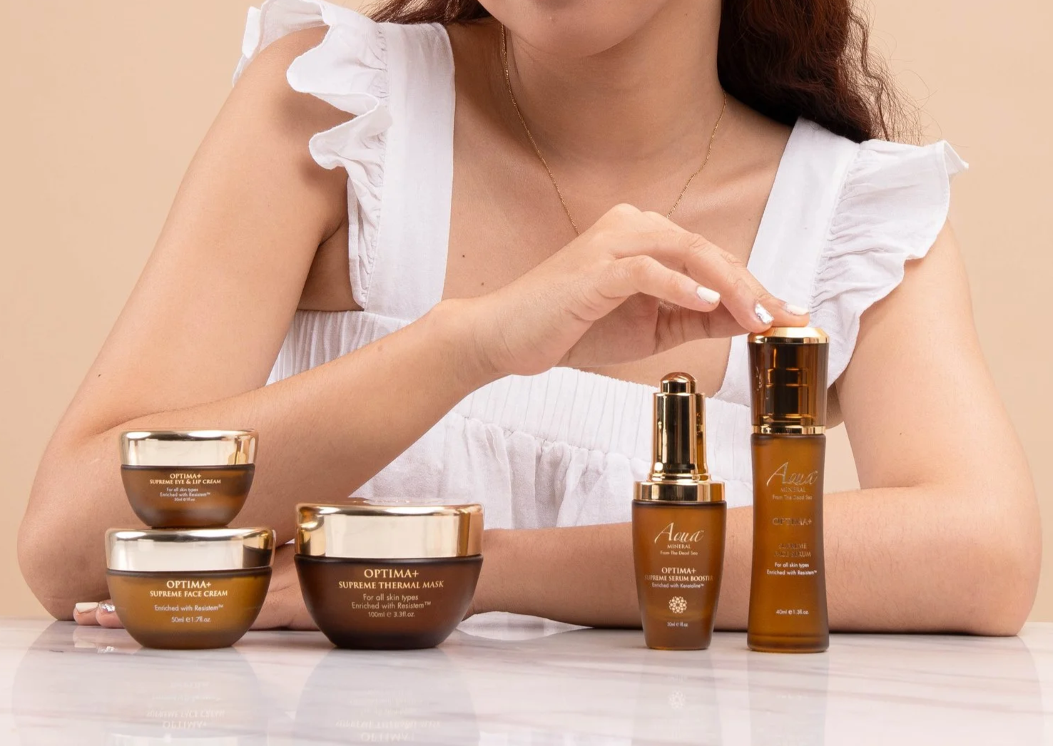 Aqua Mineral skincare collection arranged on a table with a woman holding one of the products.