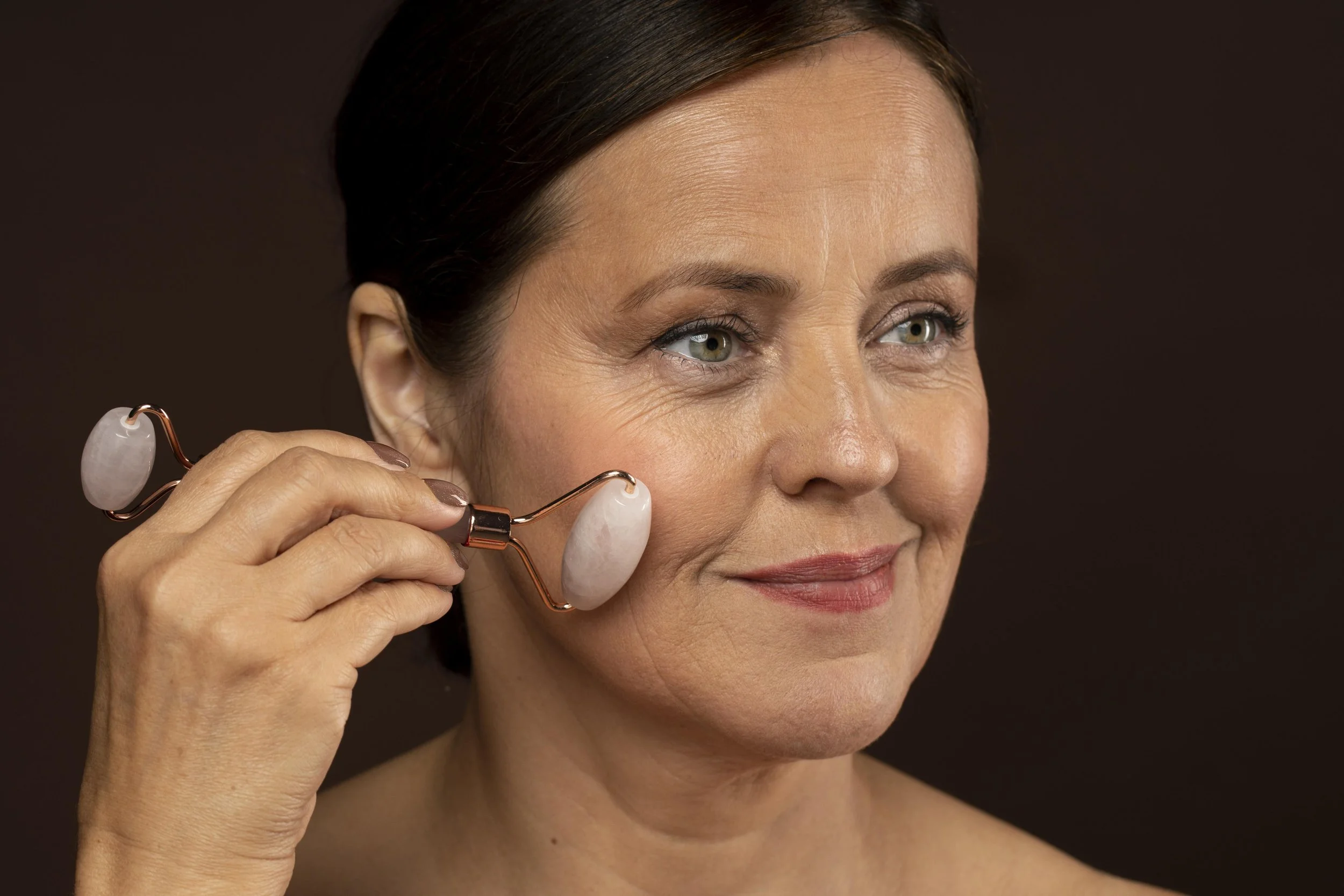 elder woman using rose quartz roller her face.jpg