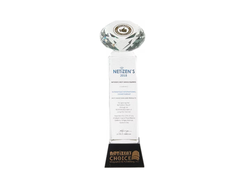 A glass award trophy with a circular top, a white rectangular middle section with blue text, and a black base with gold text. The trophy reads 'NETIZEN'S 2018' and is associated with Netizen's Choice.