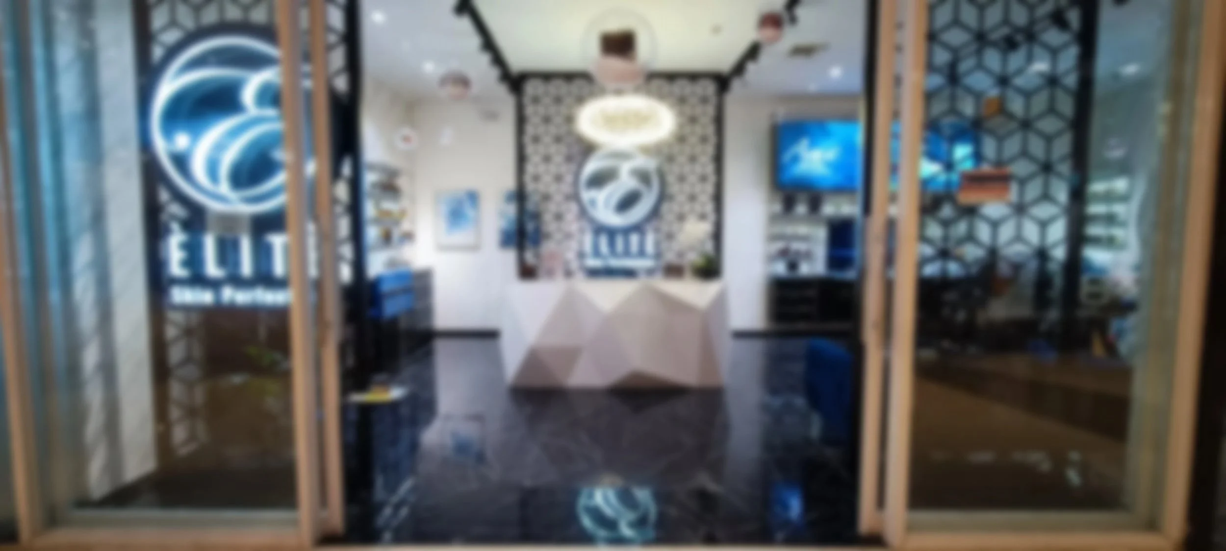 Blurred image of a modern client reception area with a service desk, wall art, flat-screen televisions, and decorative partition walls, featuring a Domino's pizza logo on the left side.