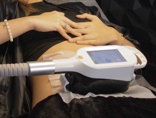 Person receiving a medical treatment using a handheld device on their abdomen.