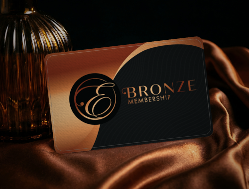 A bronze membership card with a black and gold design, placed on brown satin fabric, with a gold-colored vase in the background.