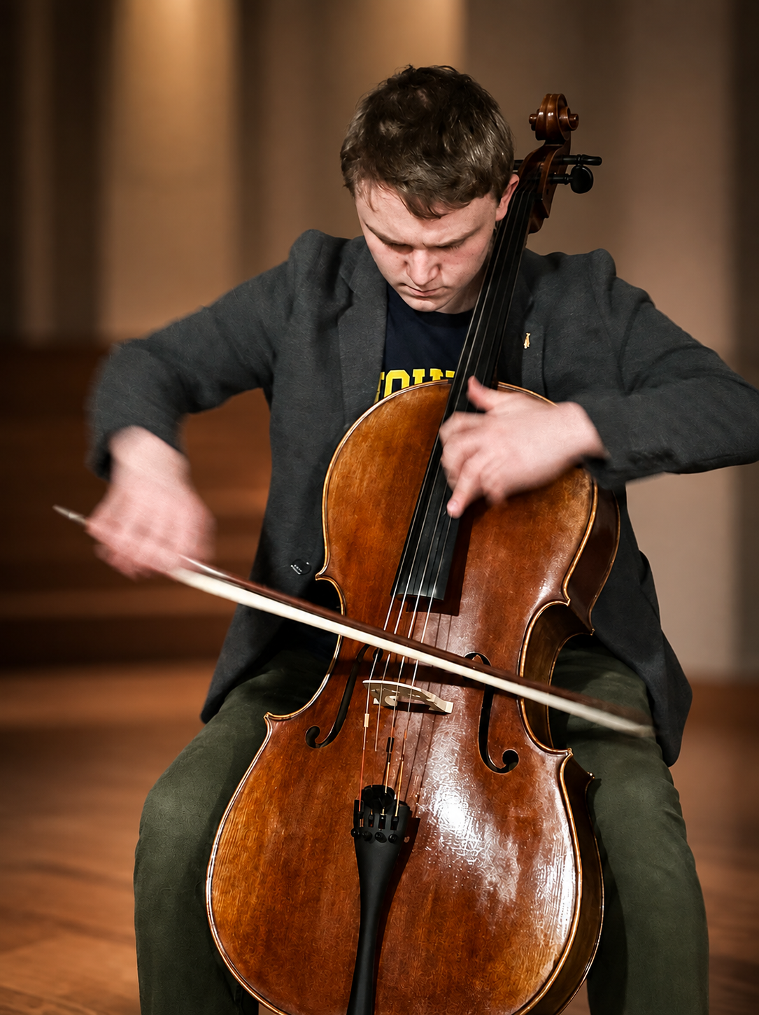 Young man playing a cello in a concert hall.