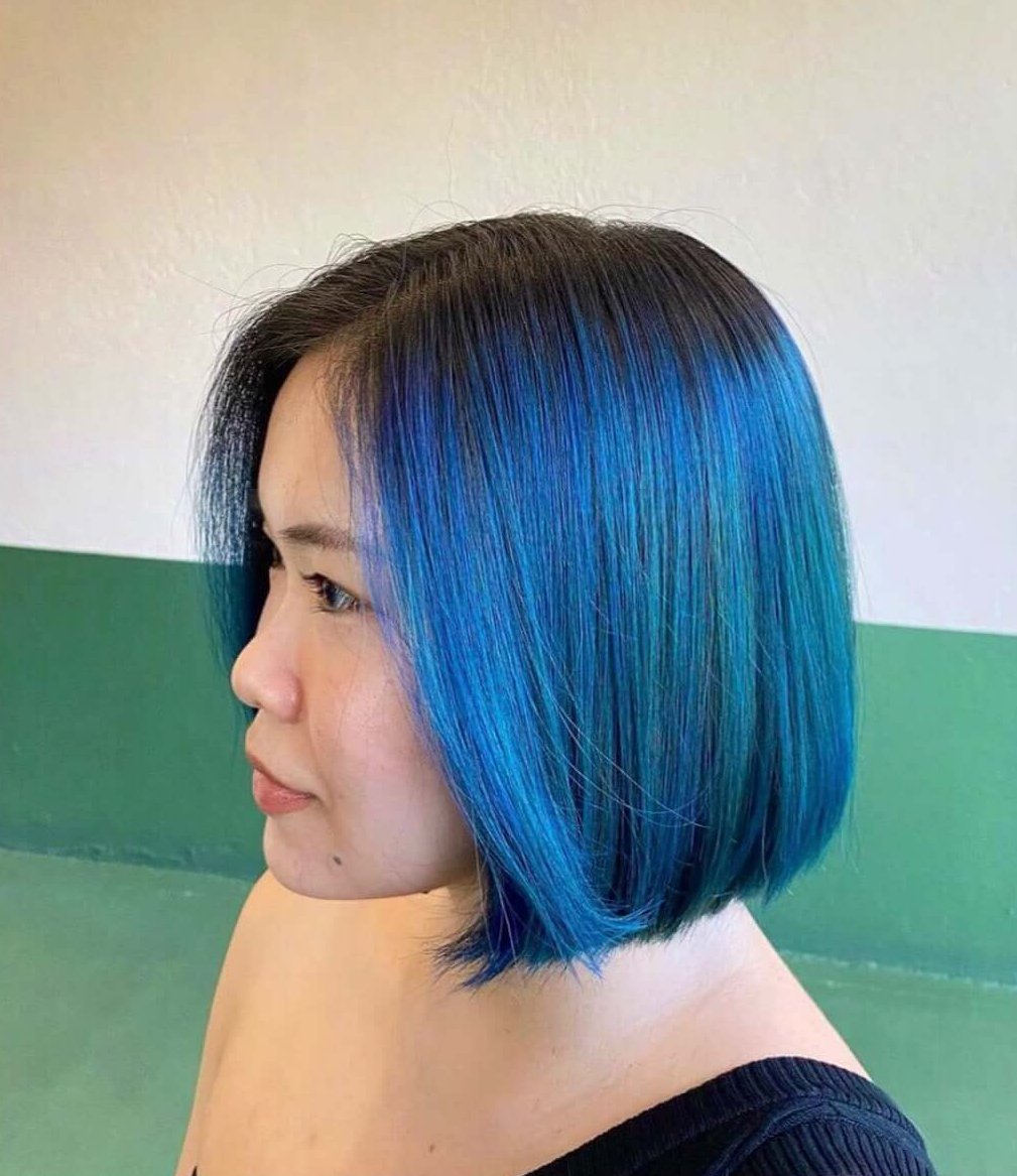 A woman with short hair dyed with a gradient from black to bright blue.