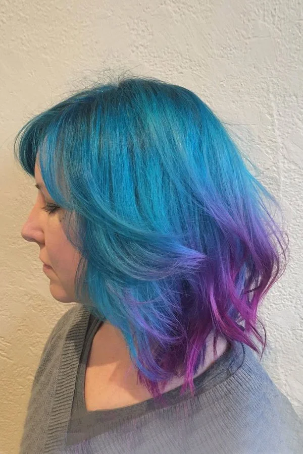 Side view of a woman with shoulder-length hair dyed in shades of blue and purple.