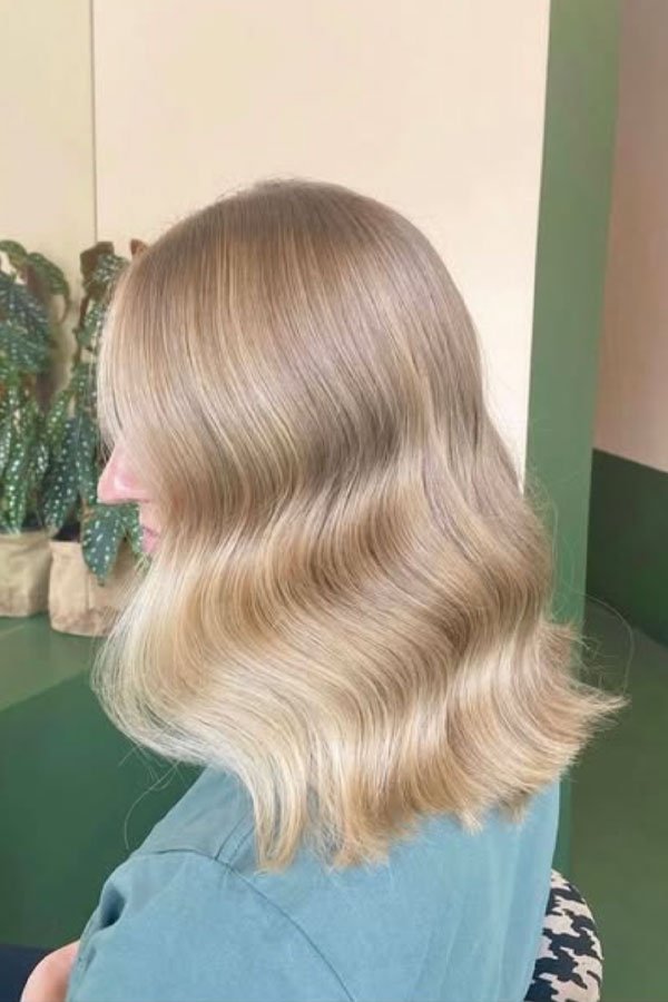 Side view of a woman with long, blonde, wavy hair.