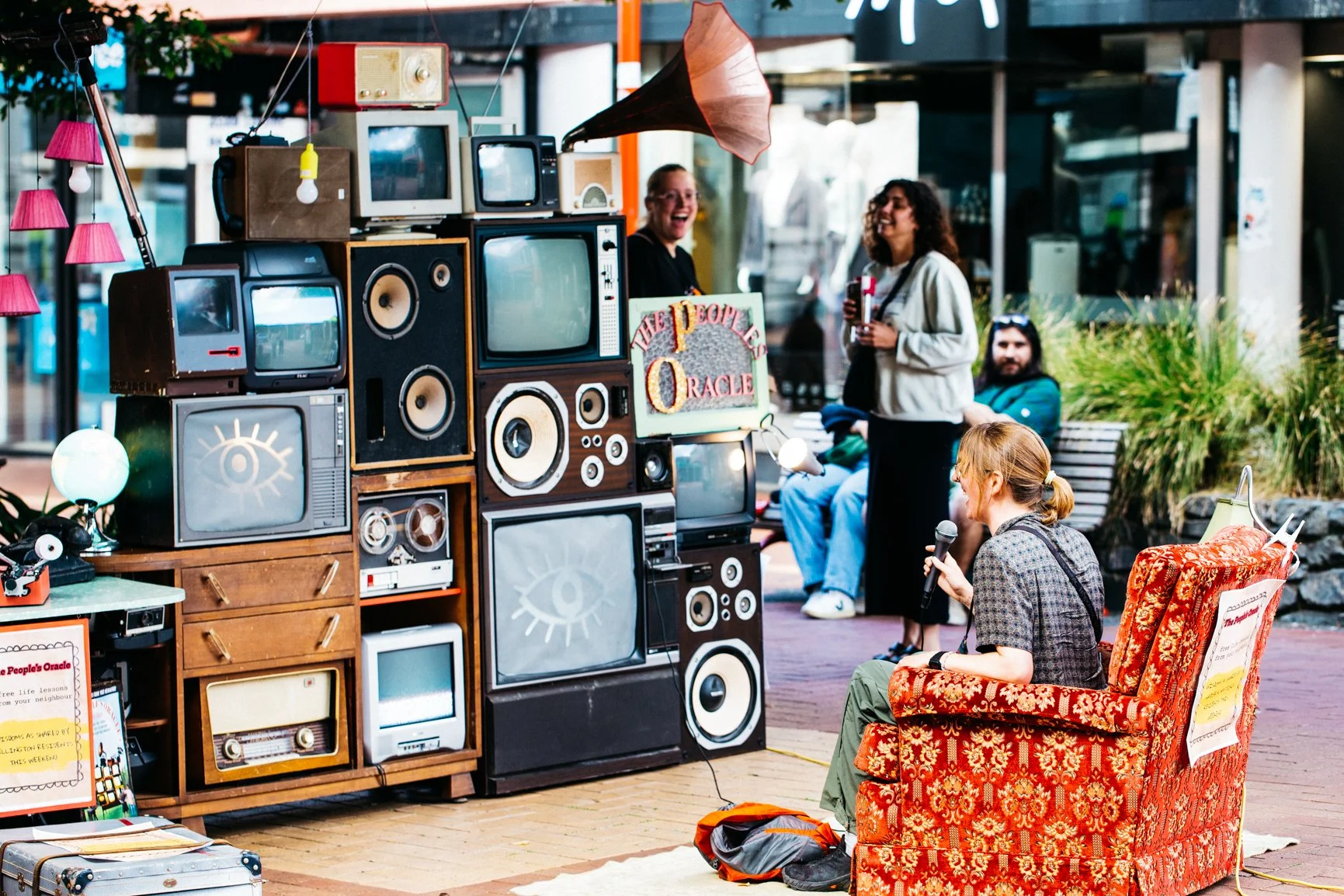 People performing a musical activity with vintage televisions and speakers outside in a casual setting.
