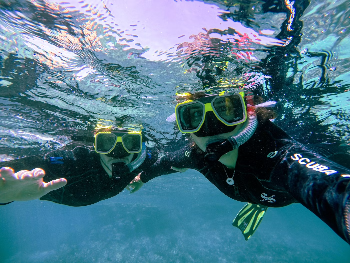 Dos personas haciendo buceo con equipo de snorkel en el agua, tomándose una selfie.