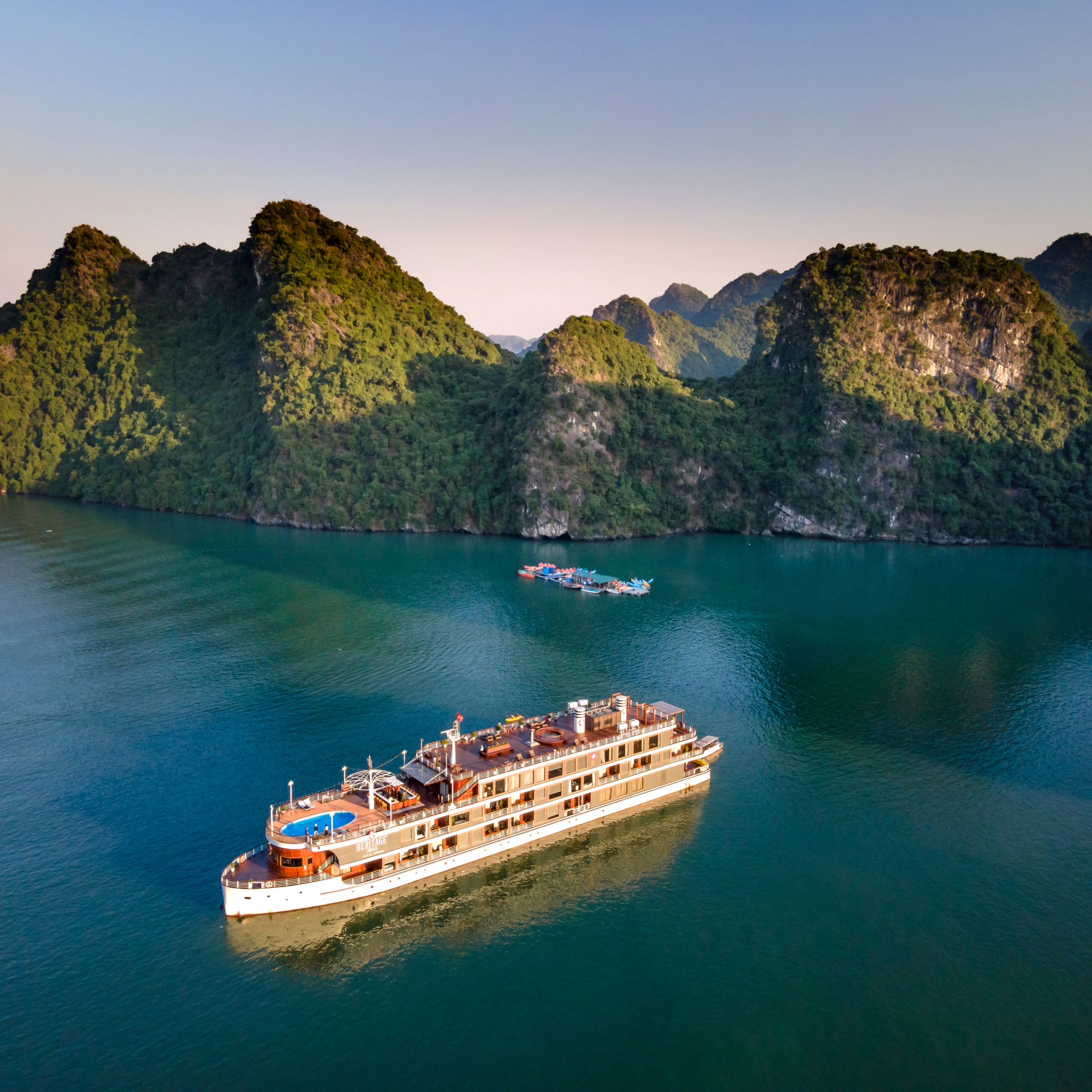 Un crucero navegando por un río rodeado de montañas verdes y rocosas bajo un cielo despejado.