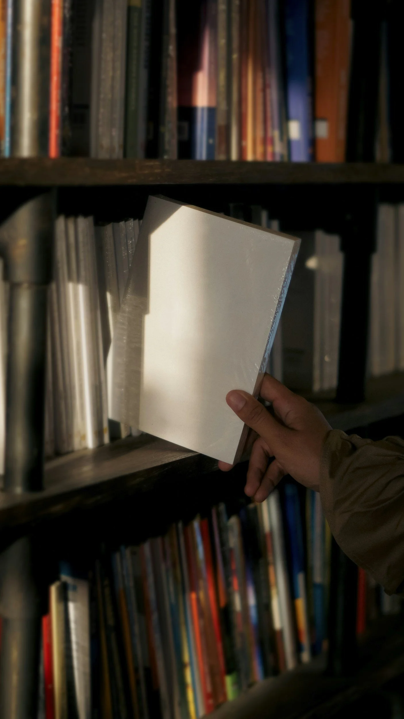 A person selecting a book from a bookshelf filled with various books.