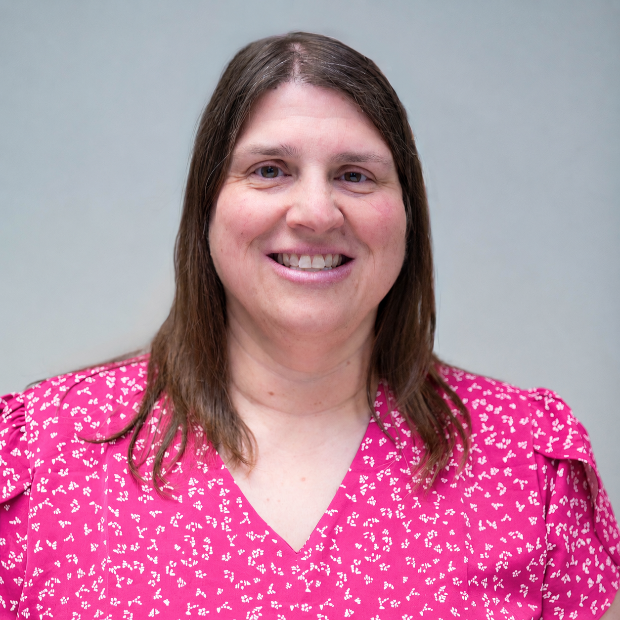 Janell Hammersberg, owner and travel advisor at Journeys by Janell, smiling in a bright pink patterned blouse.