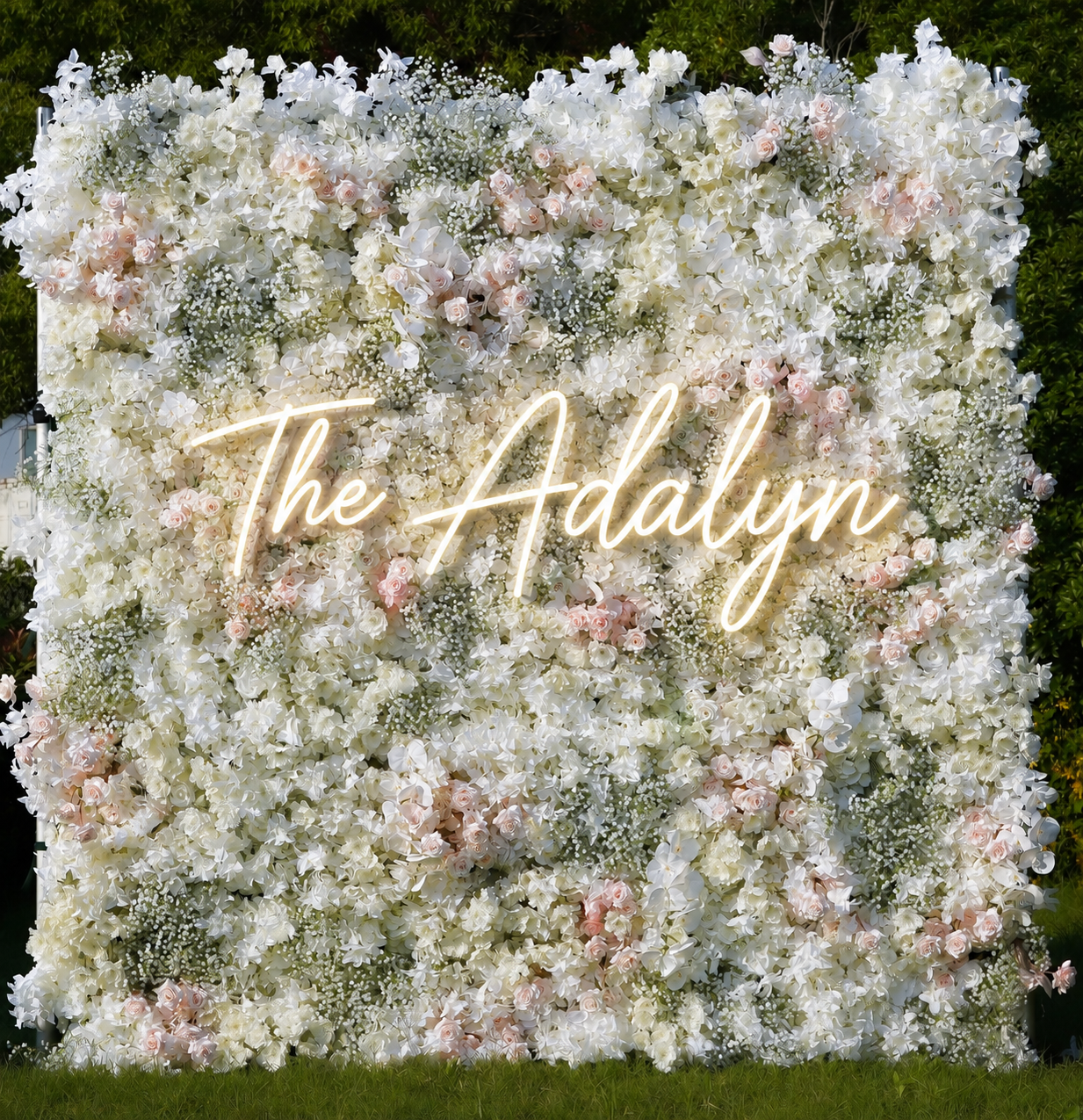 A large floral backdrop featuring white and pale pink roses, white hydrangeas, small white flowers, and greenery.