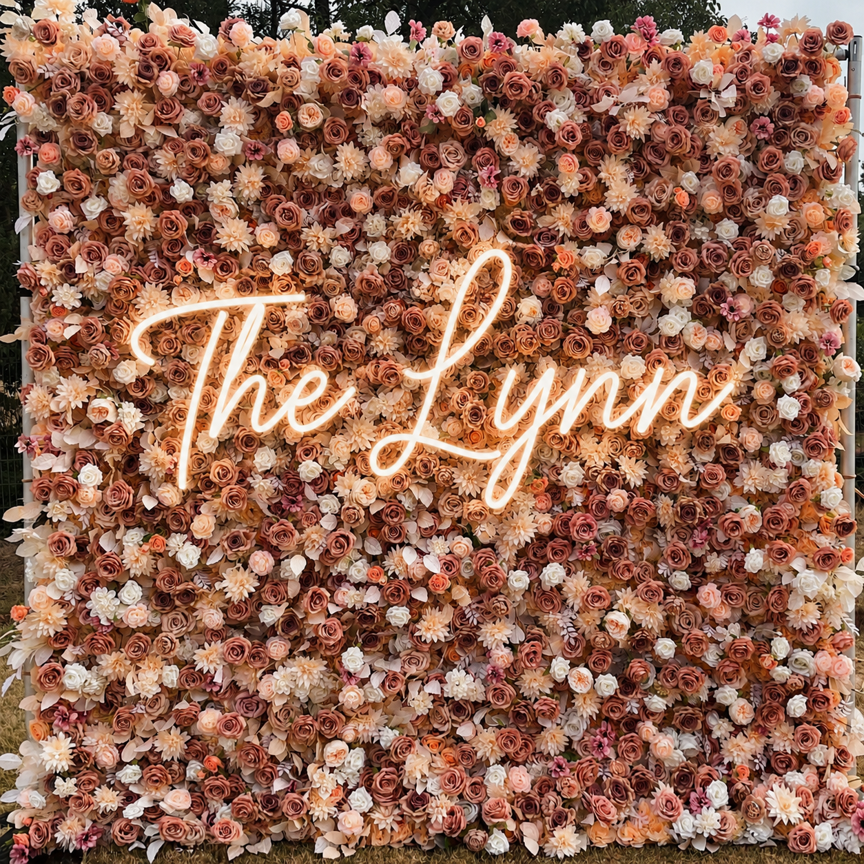 A backdrop made of numerous pink, peach, and white artificial roses and flowers.