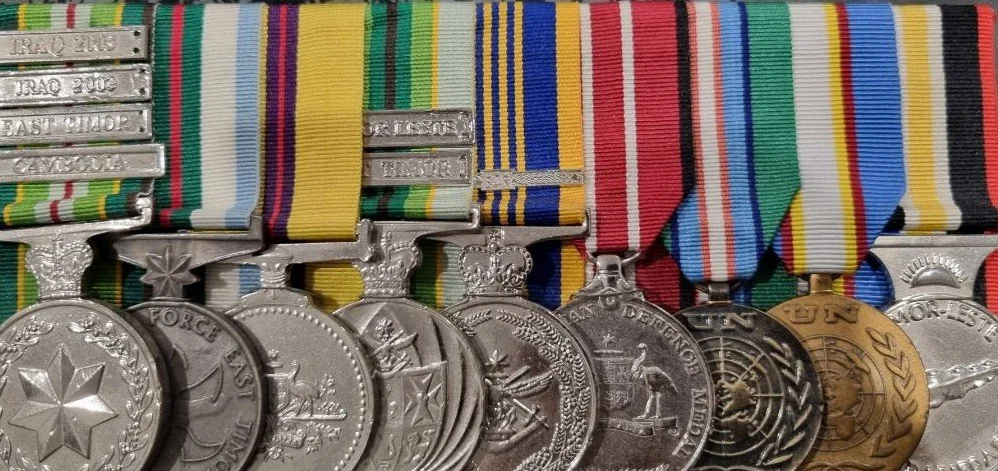 A collection of Australian military medals with various colored ribbons, displayed in a row.