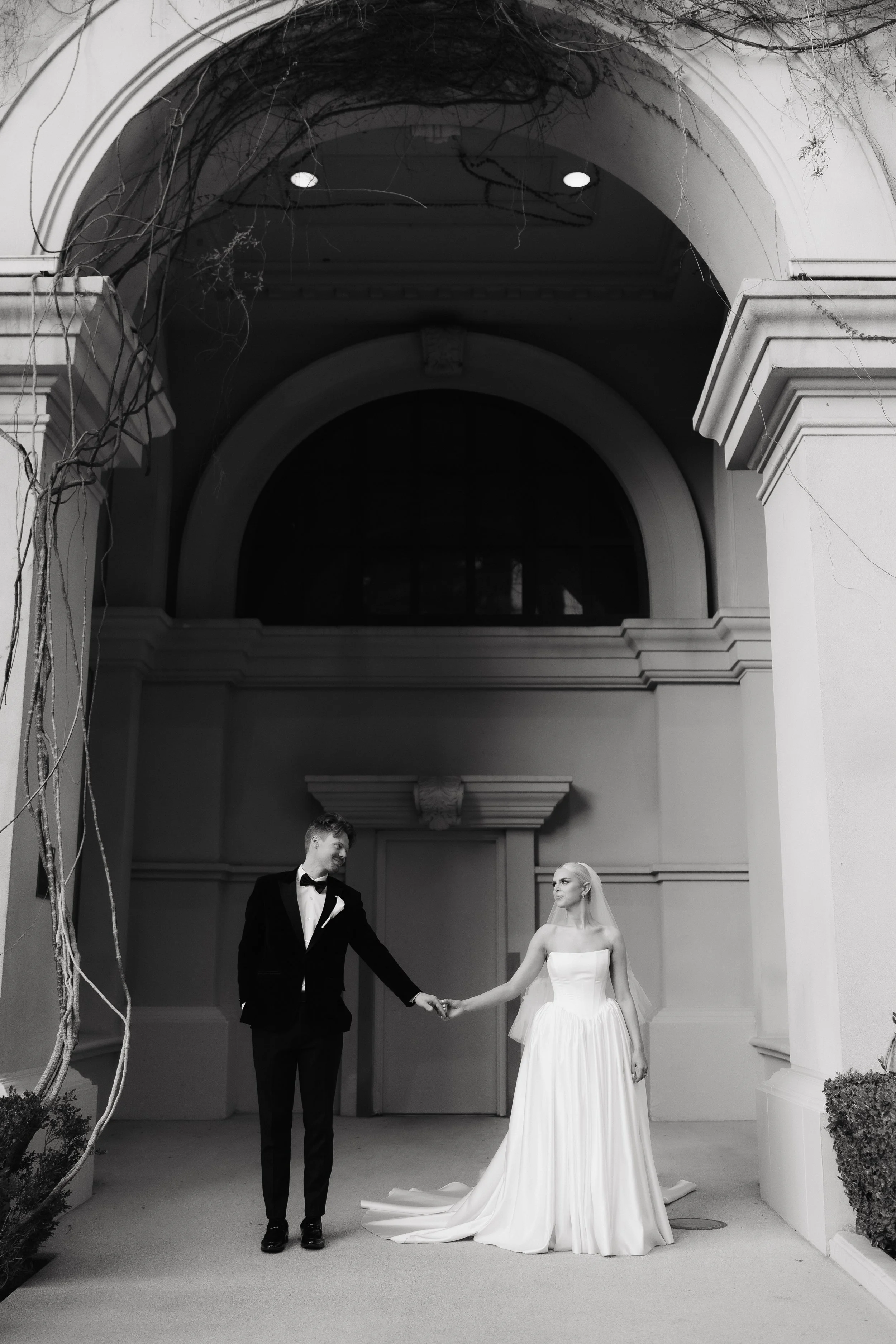 Bride and groom hold hands in front of a hotel on the Vegas strip