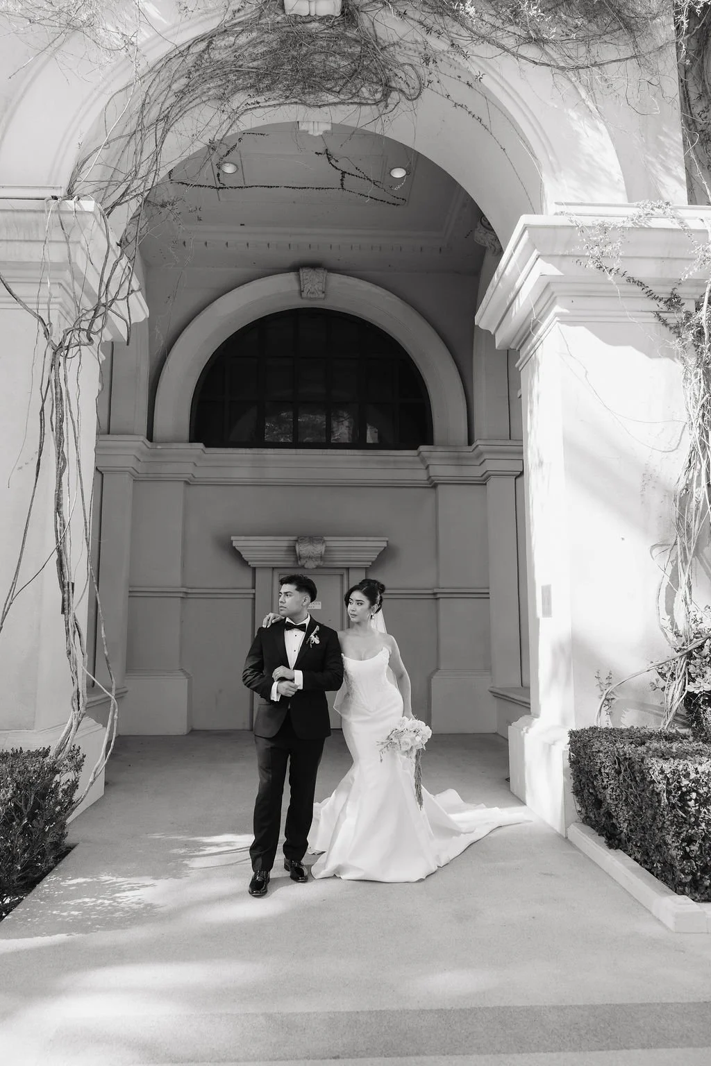 Bride and groom embracing beneath classical columns during their elegant Las Vegas wedding.