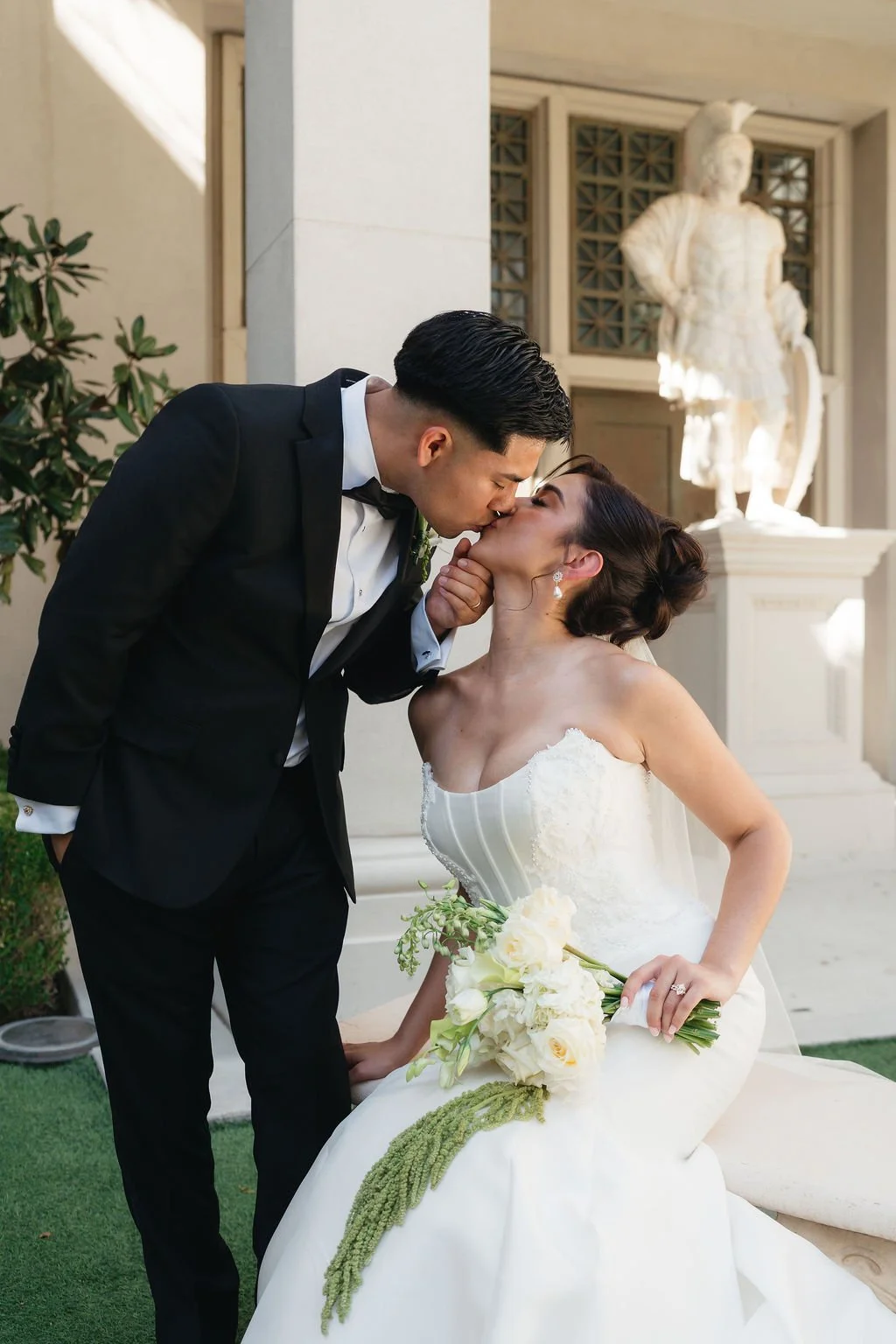 Bride and groom sharing an editorial wedding portrait beside a classical statue at an elegant Las Vegas venue.