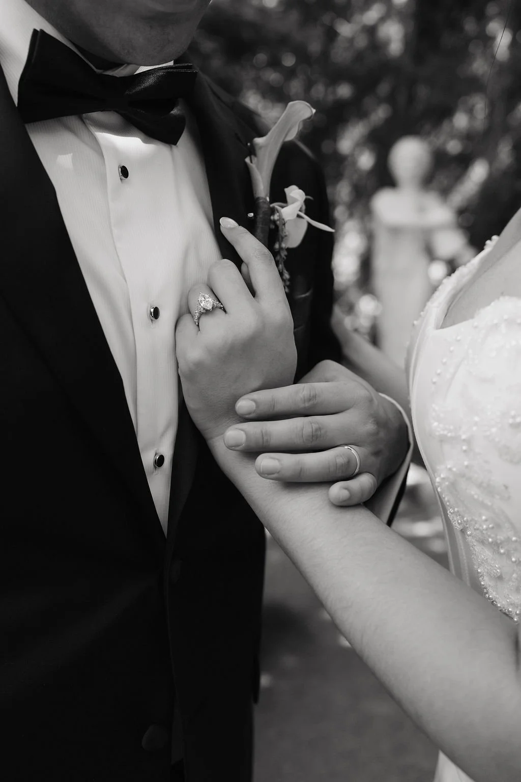 Timeless black-and-white portrait of newlyweds seated together in a sunlit garden courtyard.