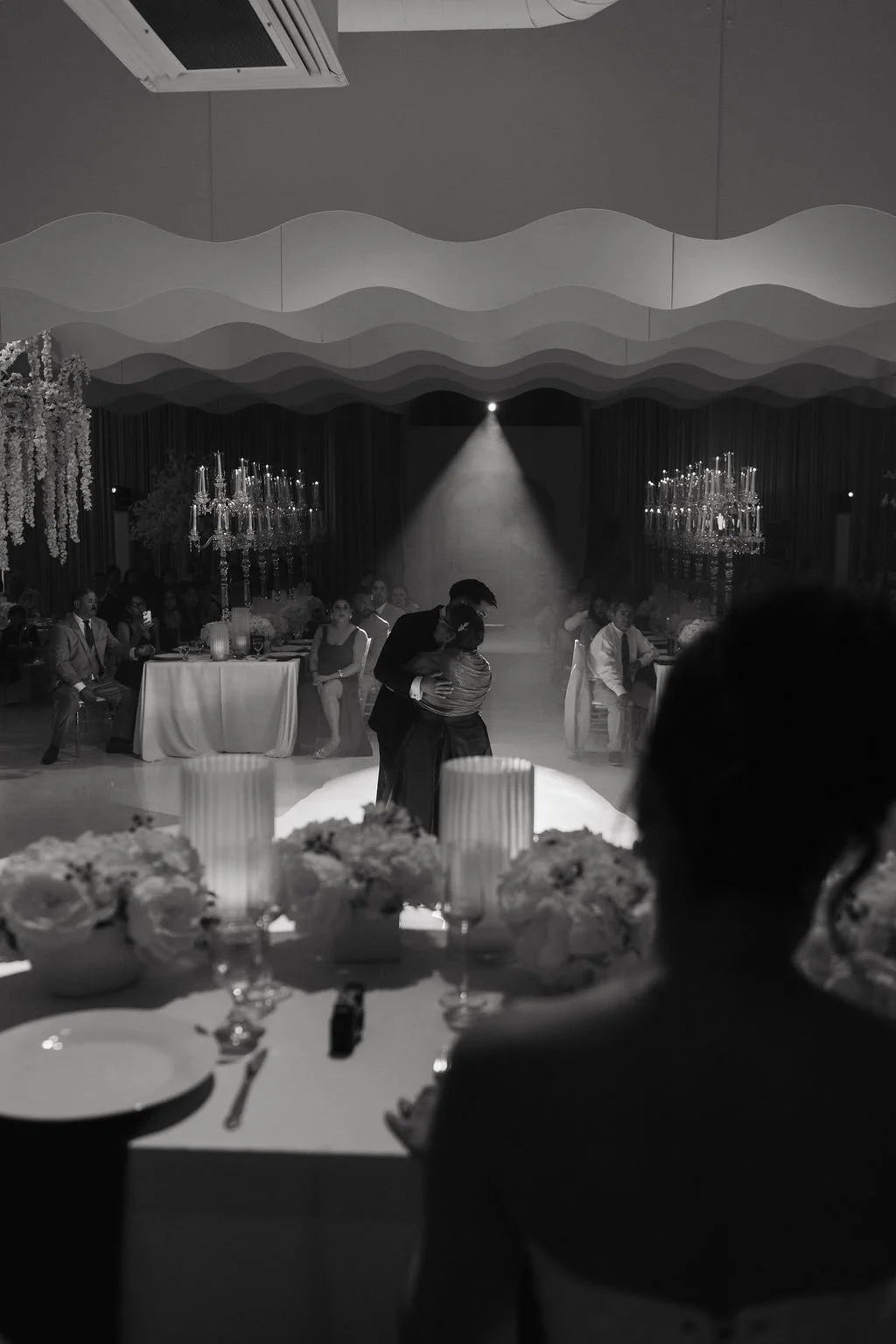 Black-and-white documentary photograph of a bride dancing with her father during the wedding reception.