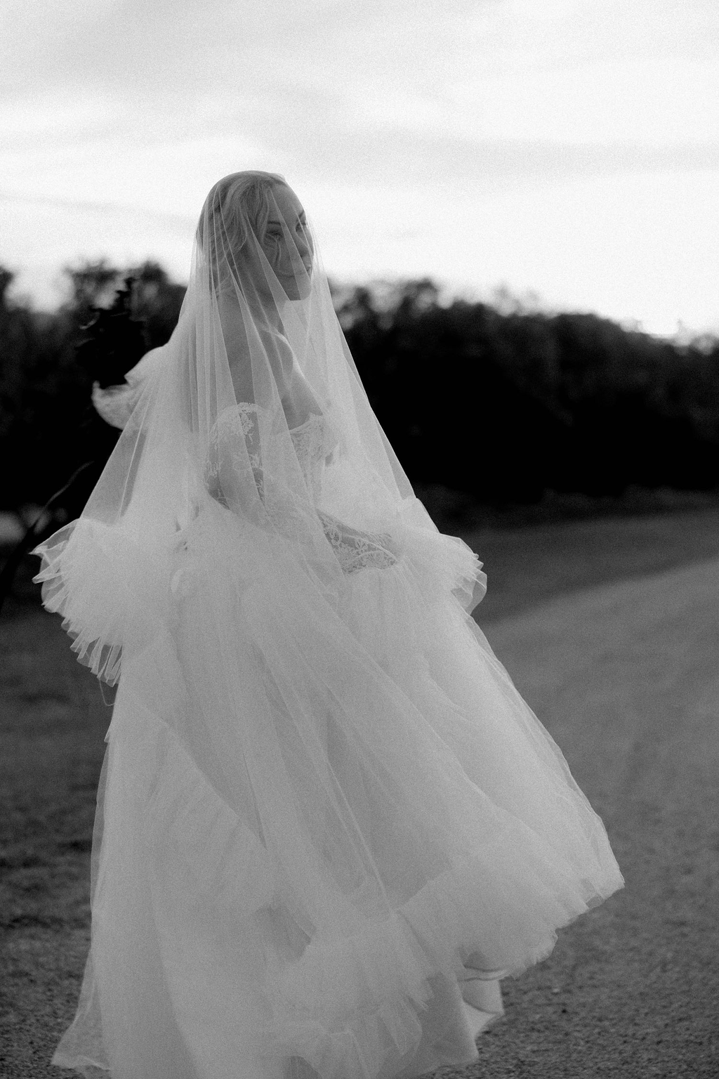 A bride wearing a wedding dress and veil standing outdoors during sunset.
Warwick wedding photographer