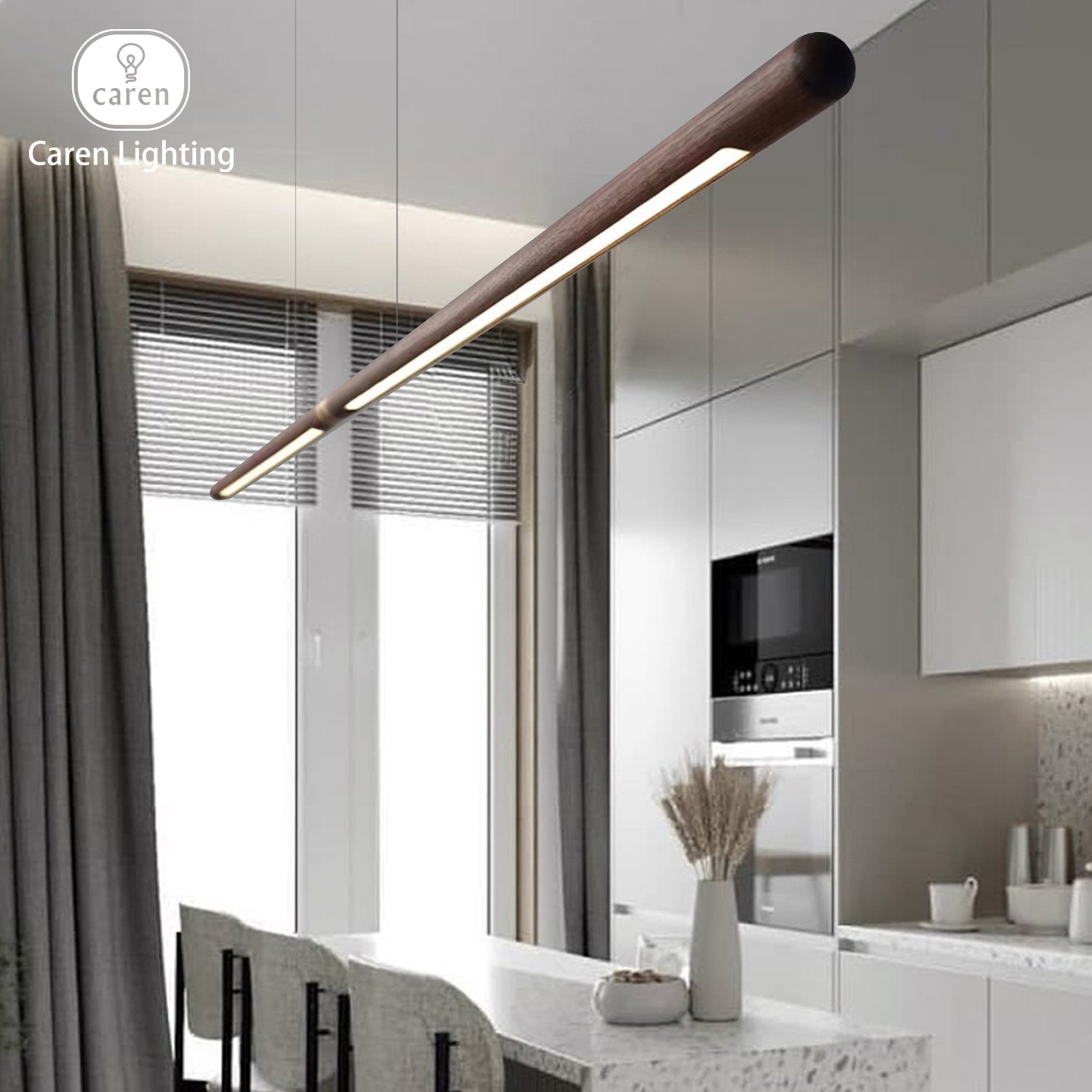 Modern kitchen with white cabinets, built-in oven, microwave, and a marble dining table with two chairs. A tall white vase with dried plants is on the table near a window with blinds and curtains. Modern lighting fixture hangs from the ceiling.
