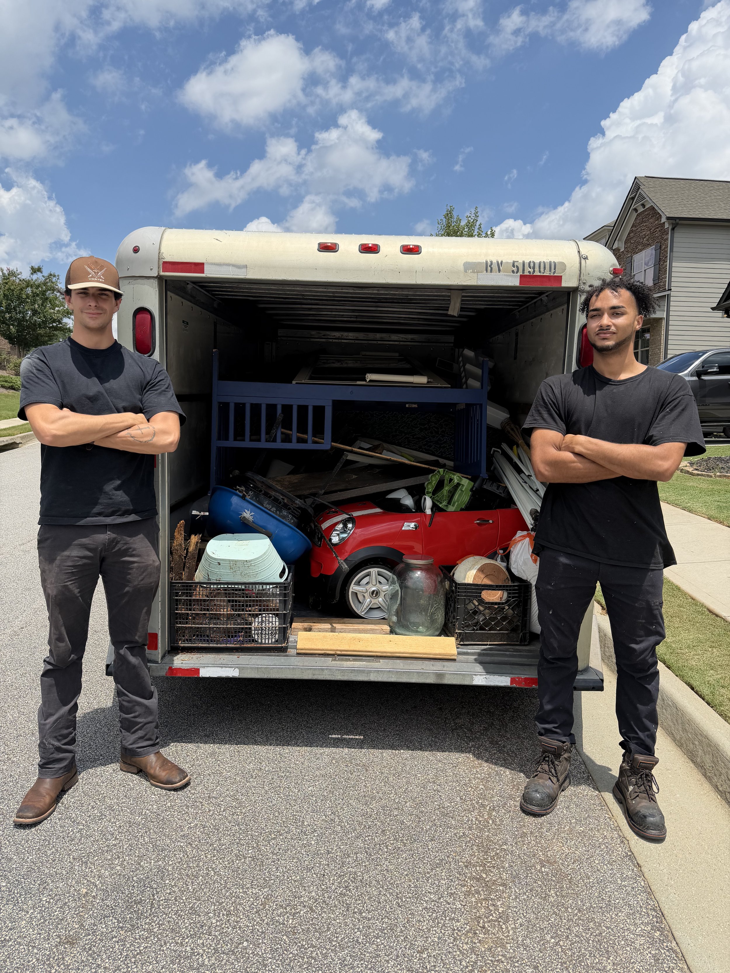 Brothers Chandler and Dillon Payne, owners of No Pain Junk Removal, with a loaded junk removal trailer in Hall County, GA