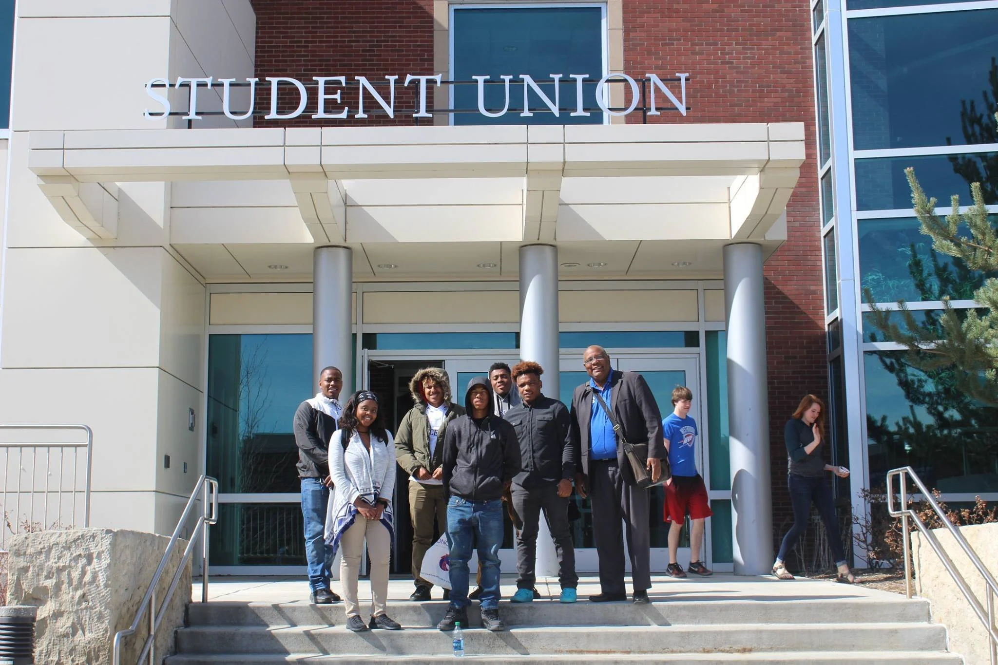 Group of people standing on steps outside a building with a sign that reads 'Student Union'.