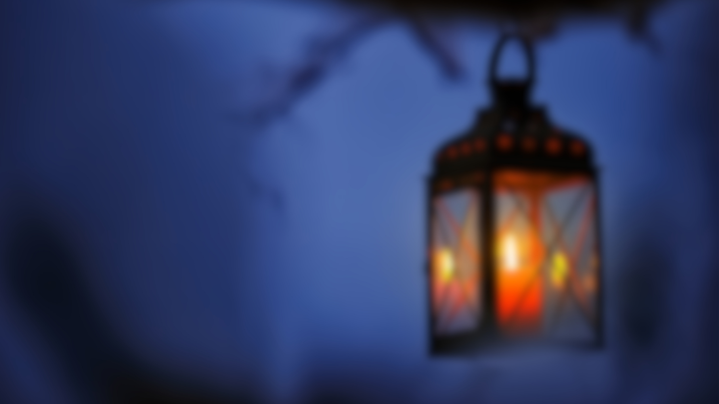 Lantern lit with flame against dark blue sky