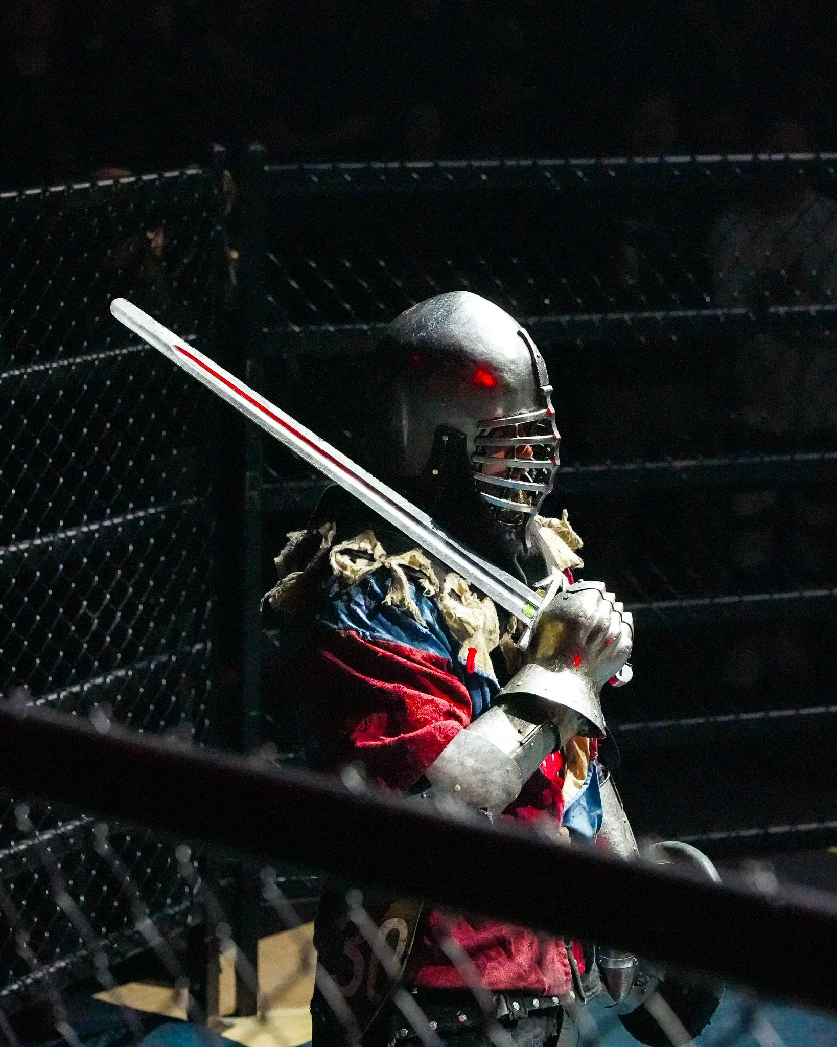 A criminal justice helmet with colorful fabric is placed on a bench with the chains of a fence or barrier in the foreground.