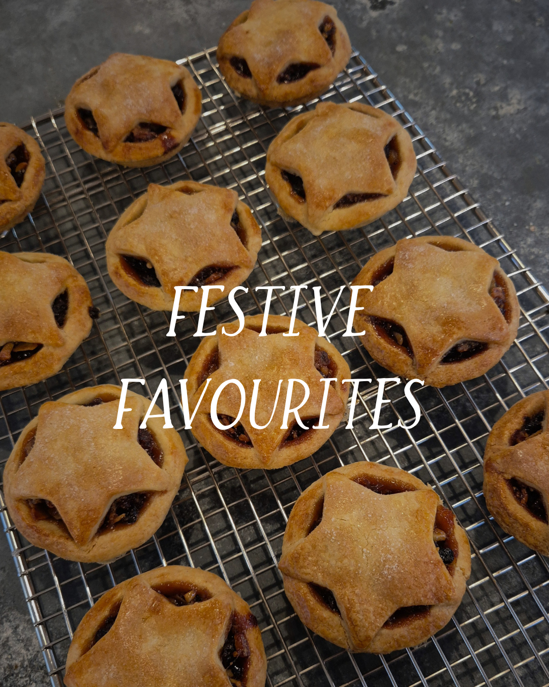 Plate of freshly baked star-shaped pastries with a dark fruit filling, cooling on a wire rack on a dark countertop, with text overlay reading 'Festive Favourites'.