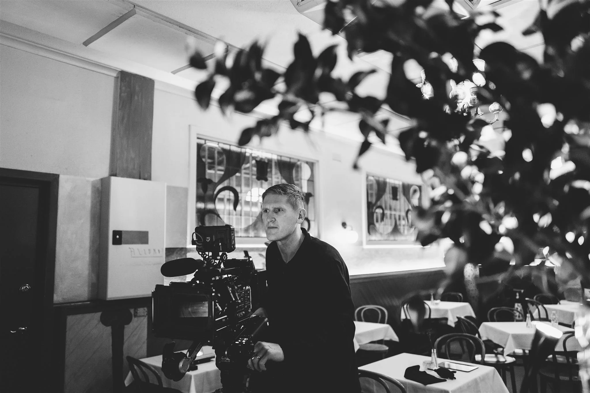 Behind-the-scenes photo of Jerome Cole operating a cinema camera on set indoors.